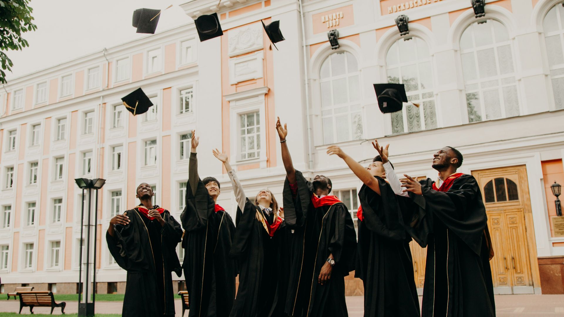 people in black academic dress standing on green grass field during daytime