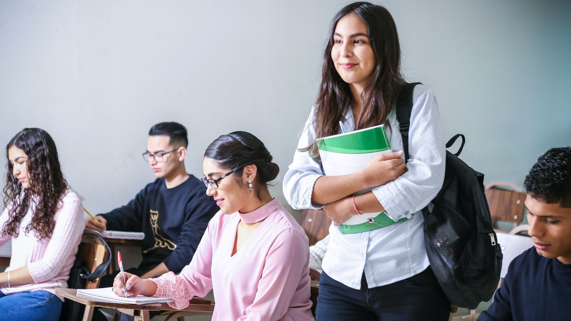 woman carrying white and green textbook