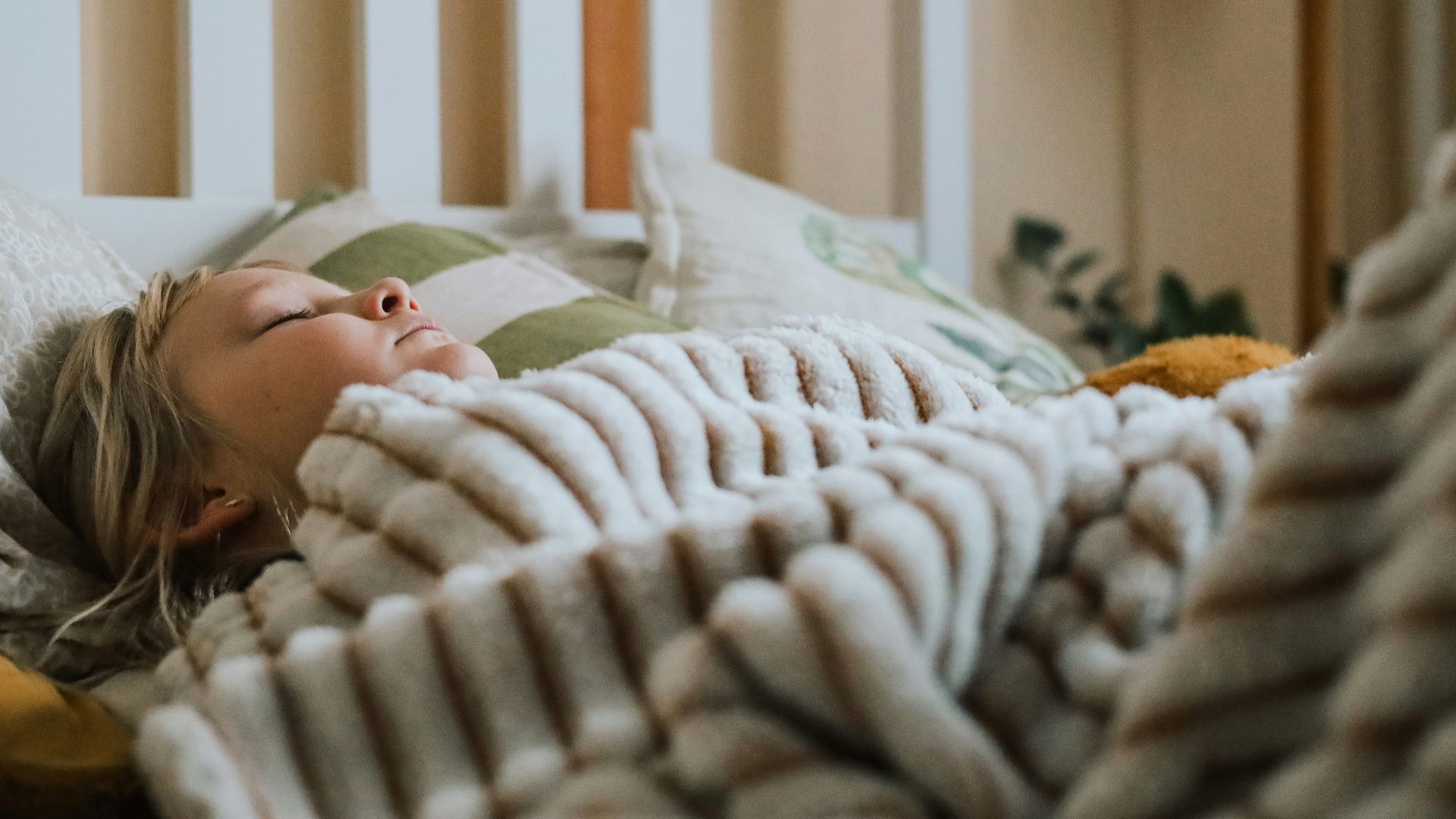 a little girl laying in bed under a blanket