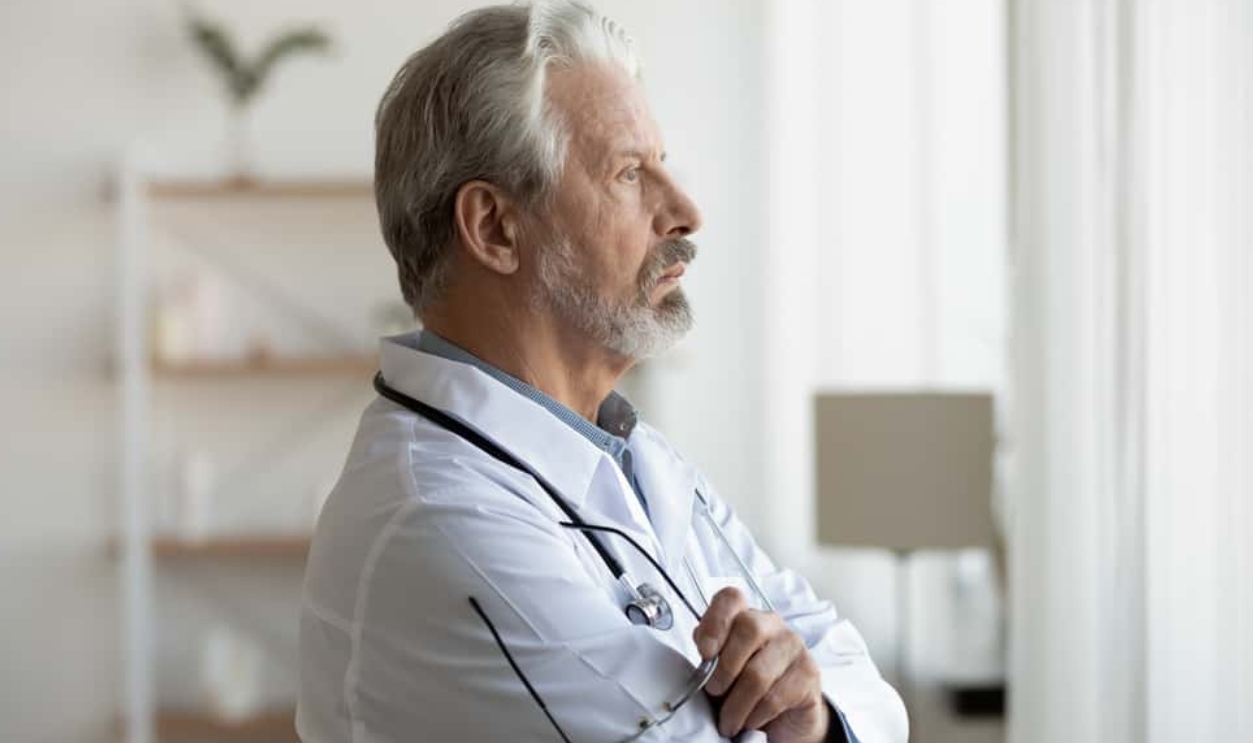 Senior Doctor Looking Through Window, Shutterstock, 1720780102