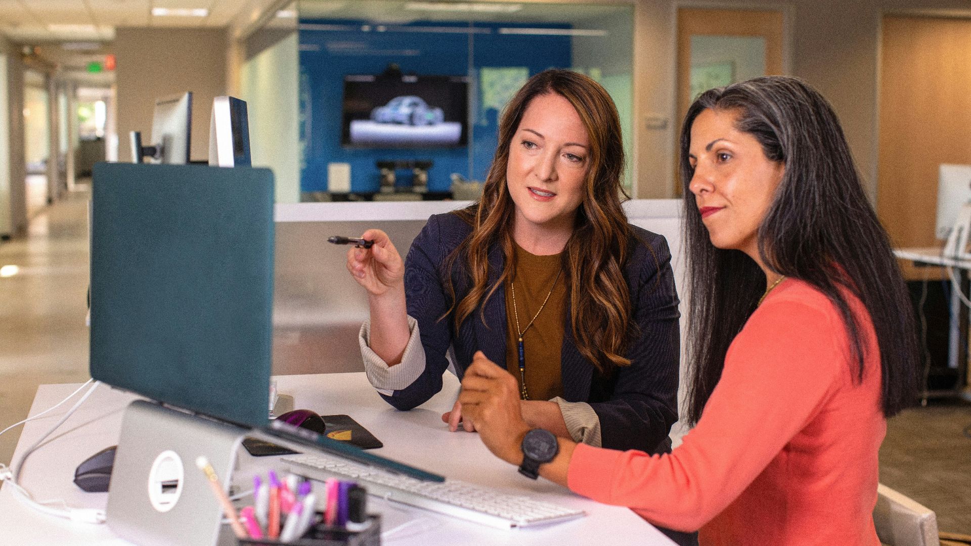 two women sitting at a table looking at a computer screen