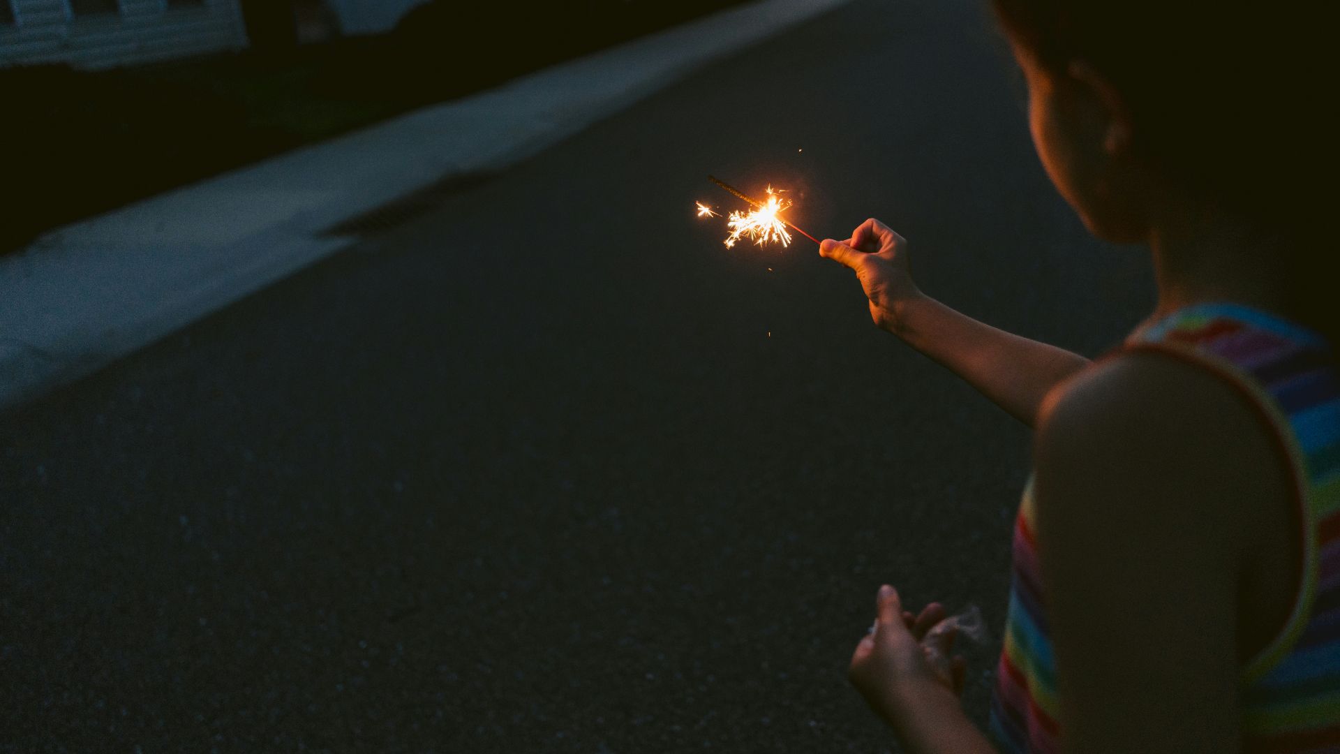 A little girl holding a lit sparkler in her hand