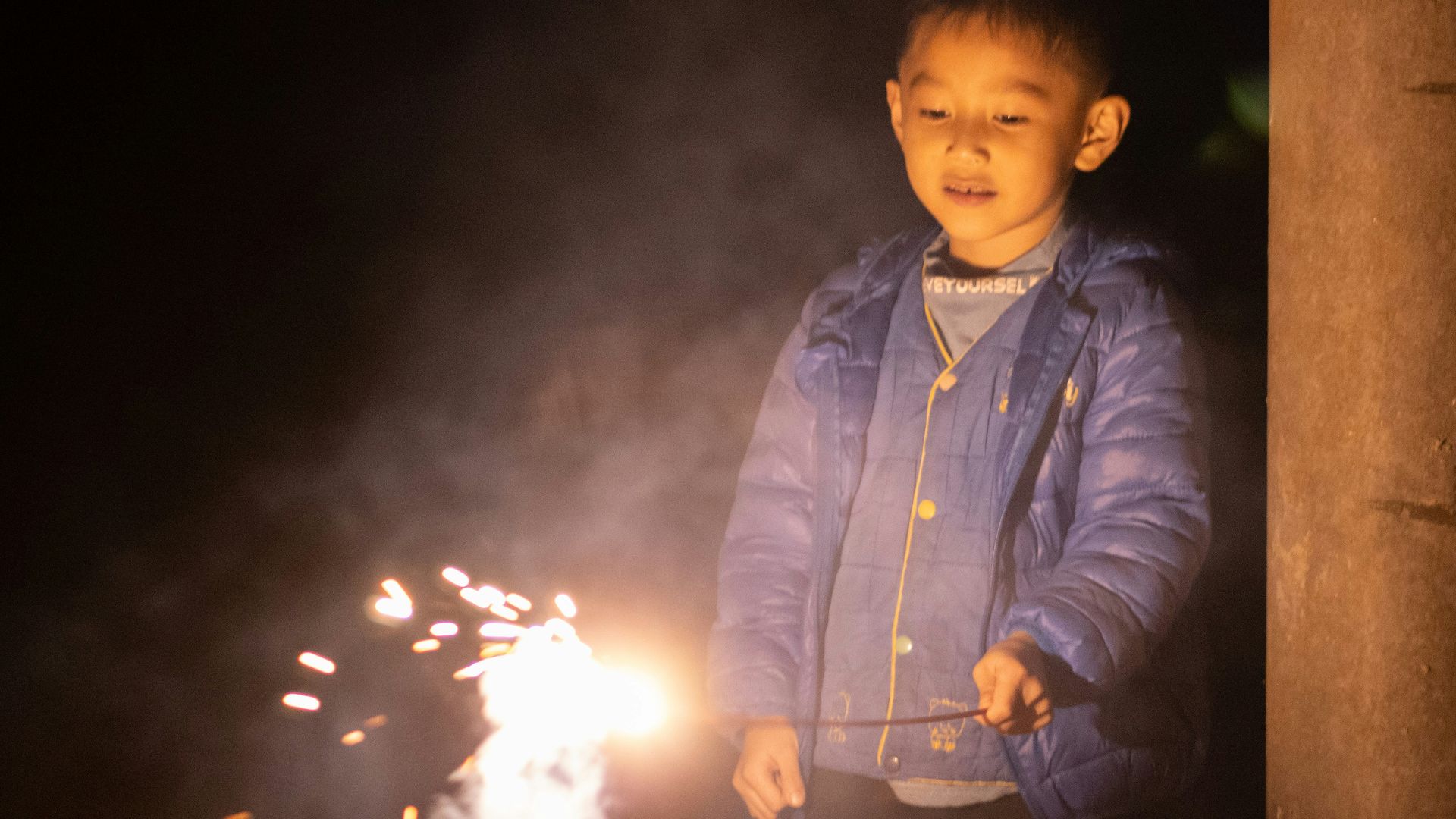 a young boy holding a sparkler in his hand