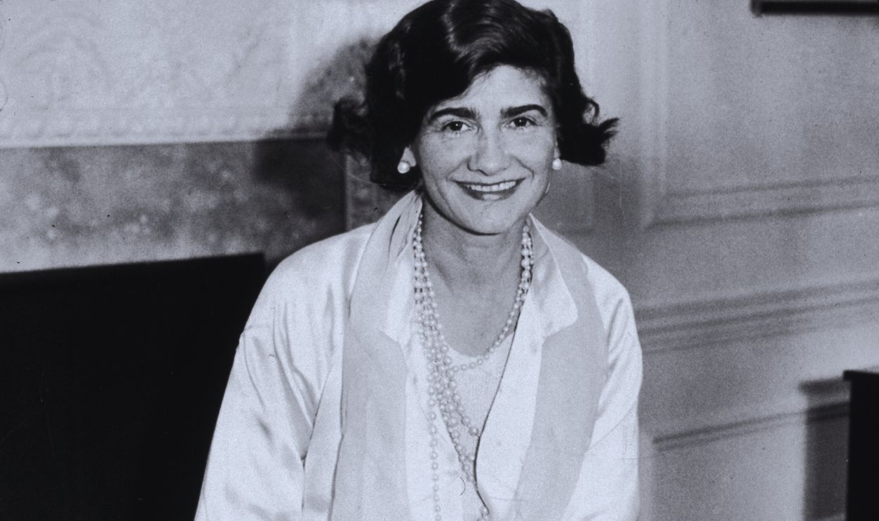 Gettyimages - 3238412, Coco Chanel 10th March 1931: Portrait of French fashion designer Gabrielle 'Coco' Chanel (1883 - 1971) posing in her suite at the Hotel Pierre during her first visit to New York City. She wears a white silk jacket and pants with pearls. 