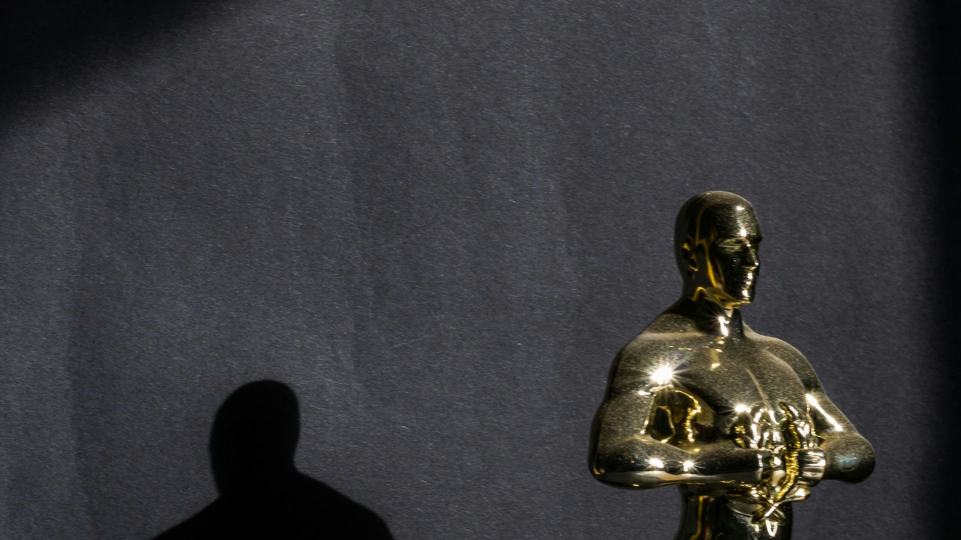 a golden statue of a man standing next to a black wall