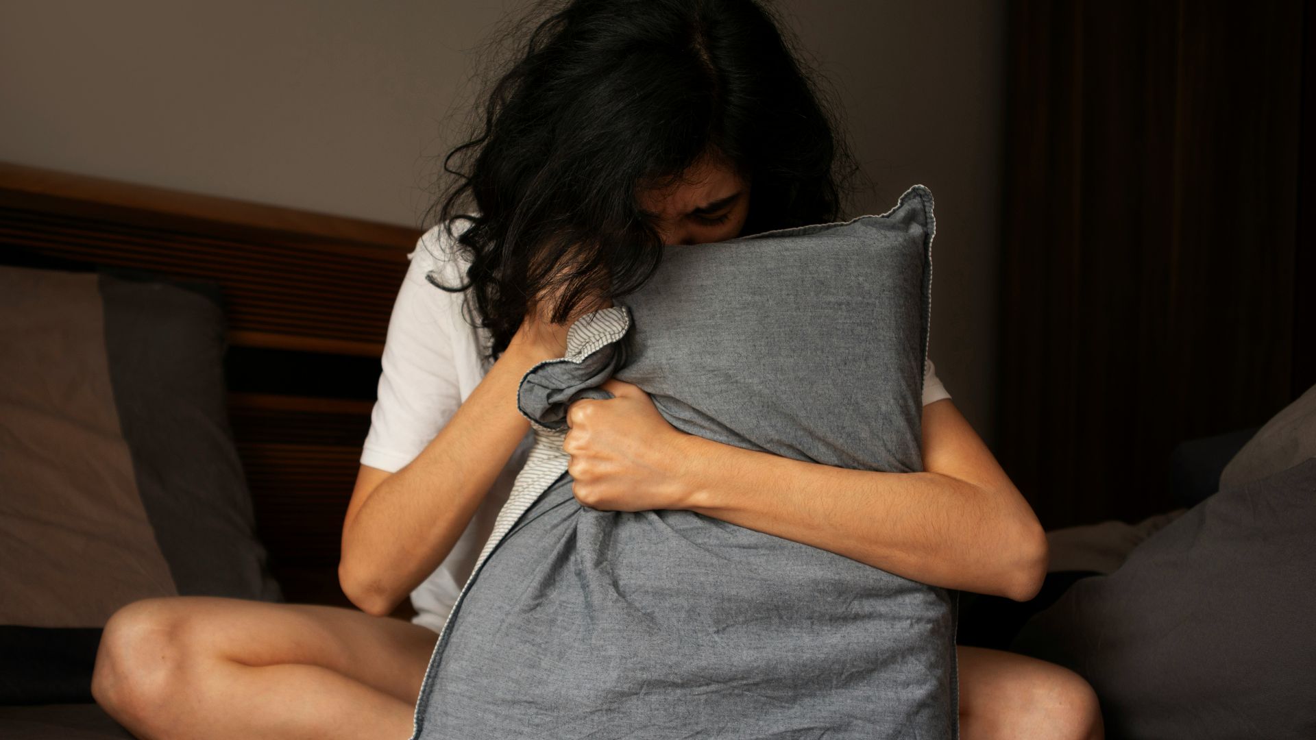 A woman sitting on a bed holding a pillow