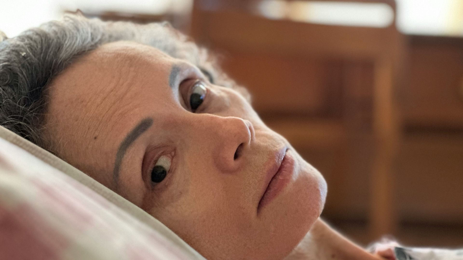 a woman laying on a bed with her eyes open