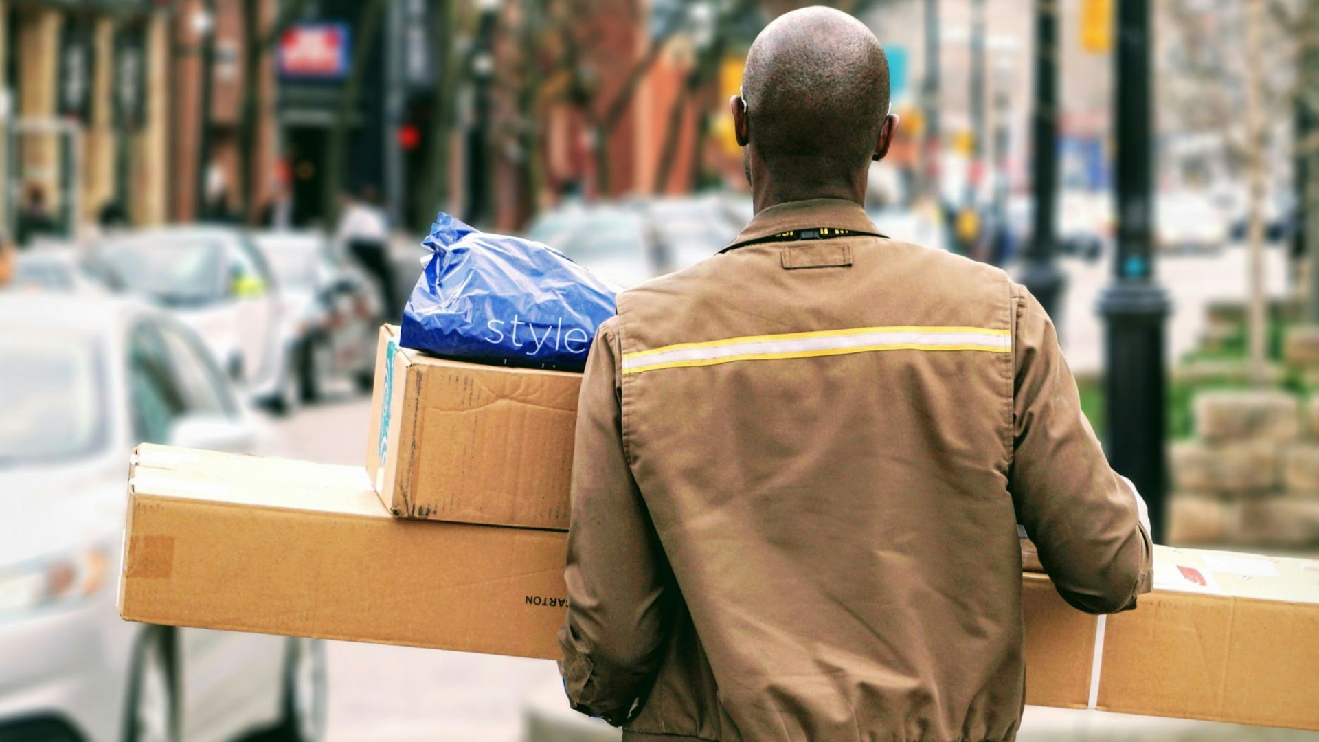 man in brown jacket beside car