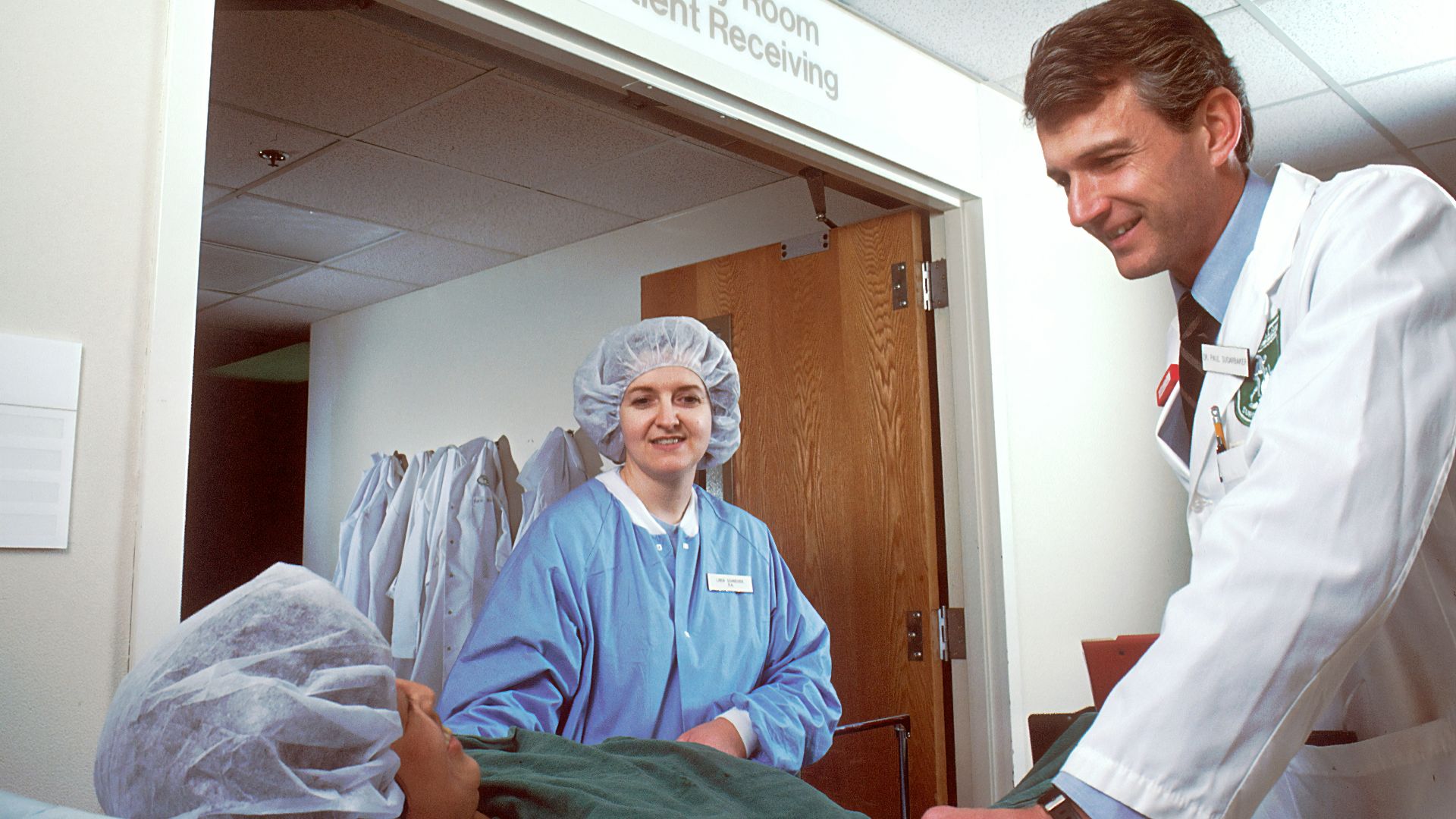 woman in blue scrub suit standing beside woman in white robe