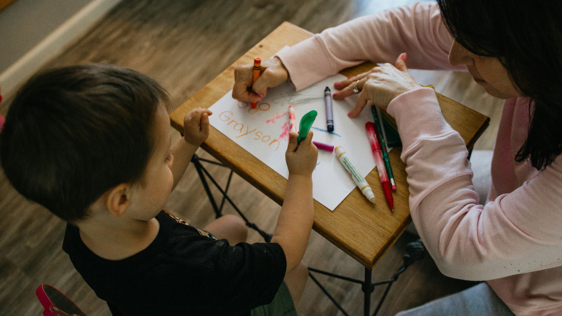 boy in white long sleeve shirt writing on white paper