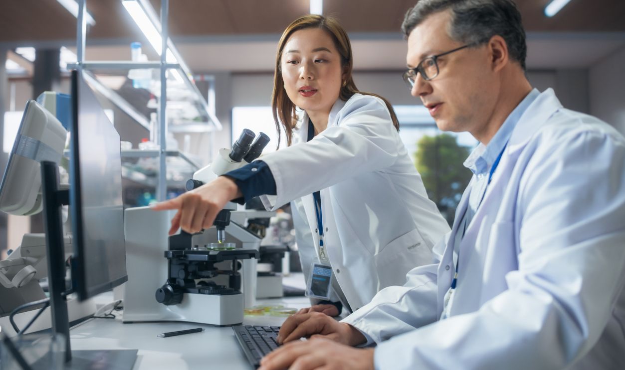 Asian Female Medical Supervisor Having a Conversation with a Caucasian Scientist About a Gene Editing Research Project, Crispr Technology and Experiments. Smart Diverse Team Working in a Laboratory
