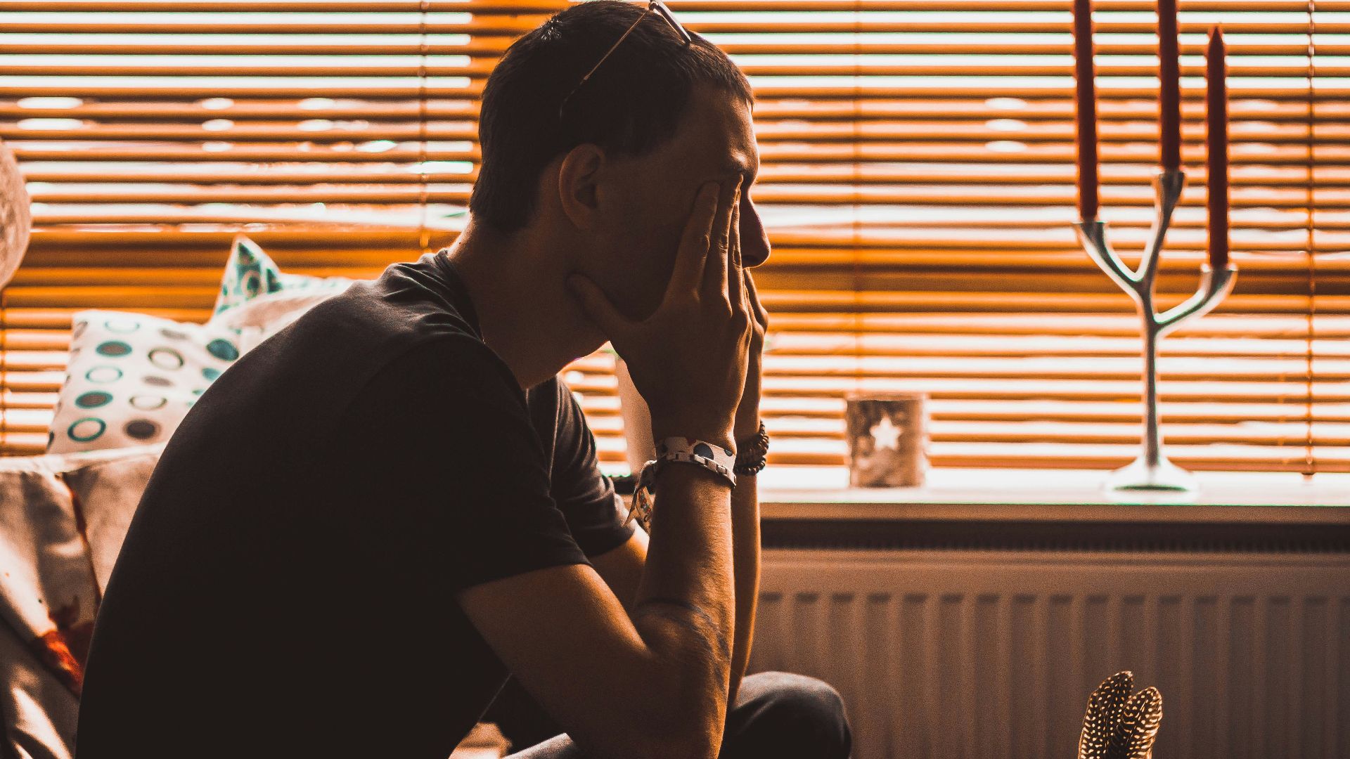 man sitting on chair covering his eyes