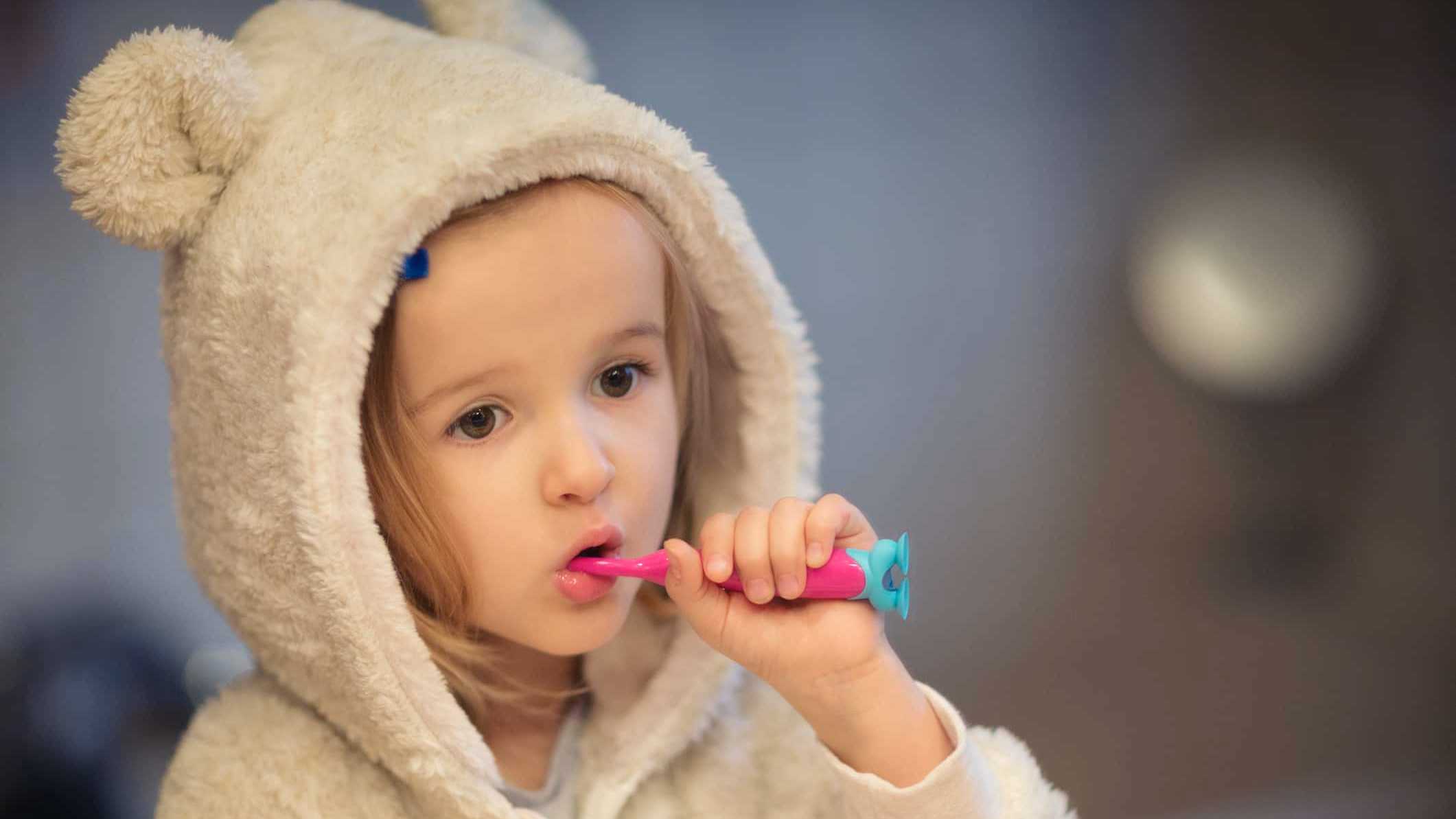Child(4-5) wearing cozy pyjamas and brushing teeth.