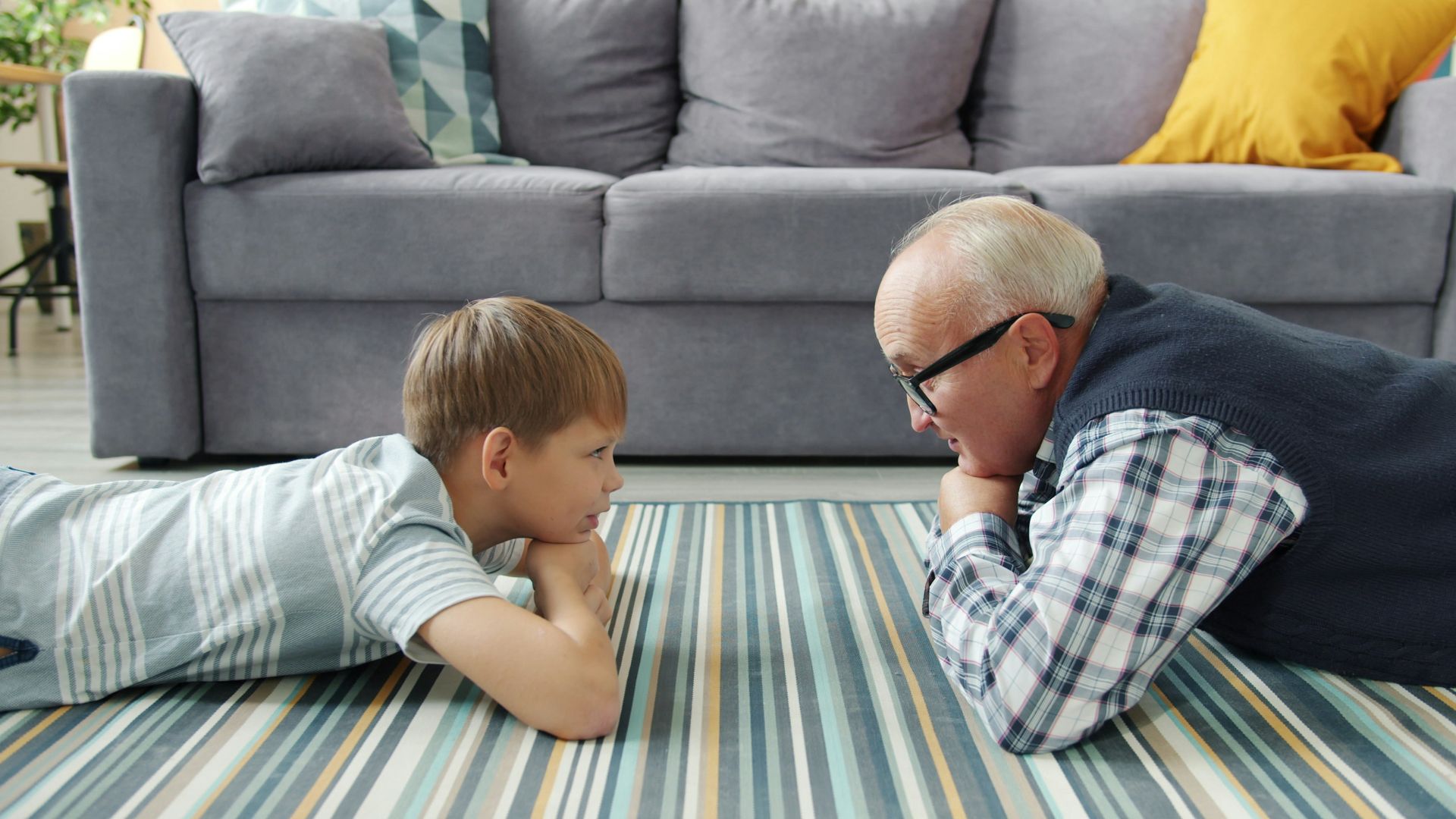 Grandfather and grandson lying on the floor talking.