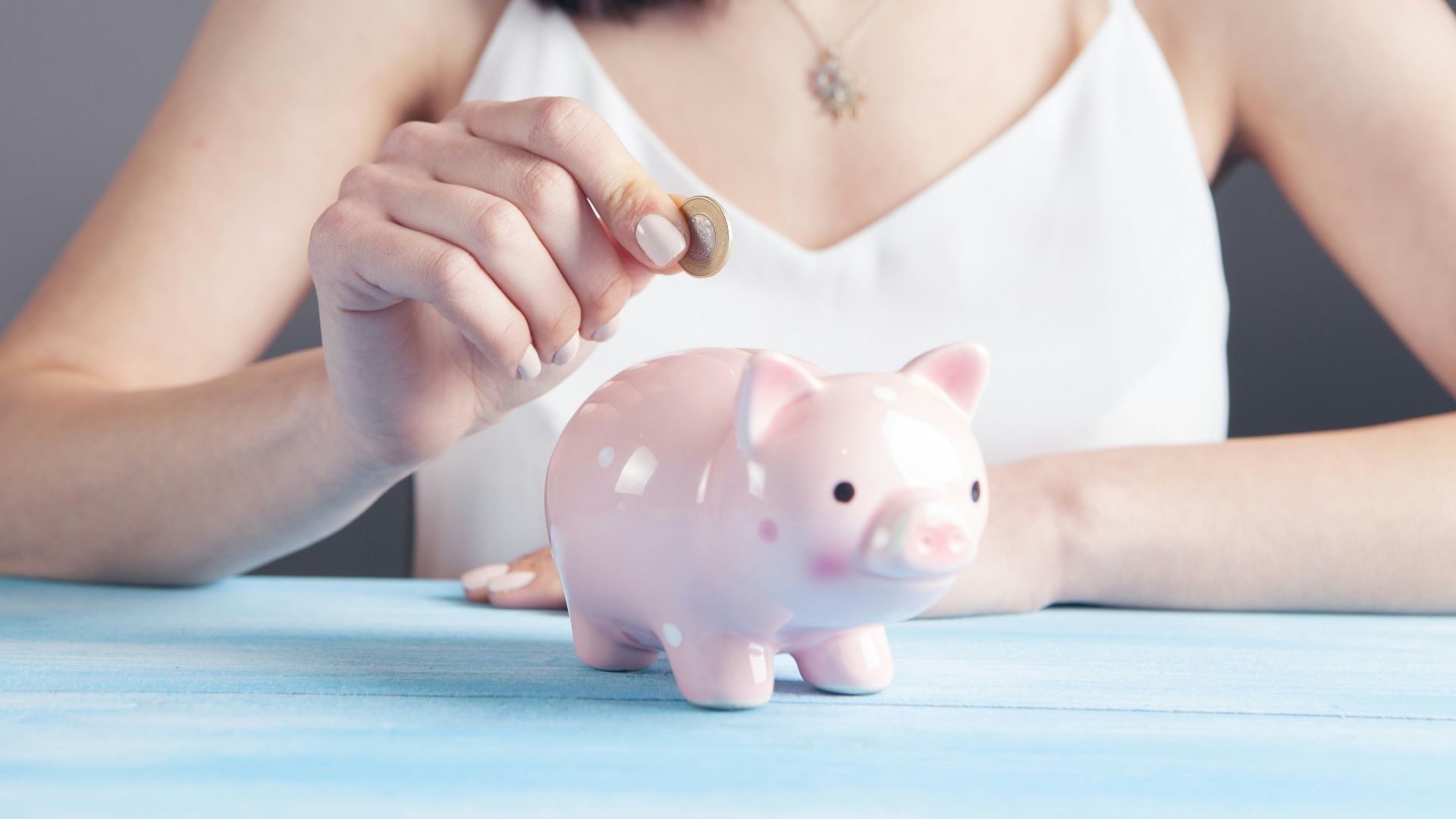 woman in white tank top holding pink pig figurine
