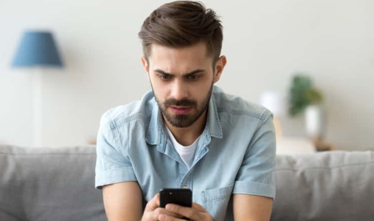 Millennial Man Sit On Couch Using Smartphone, Shutterstock, 1230909643