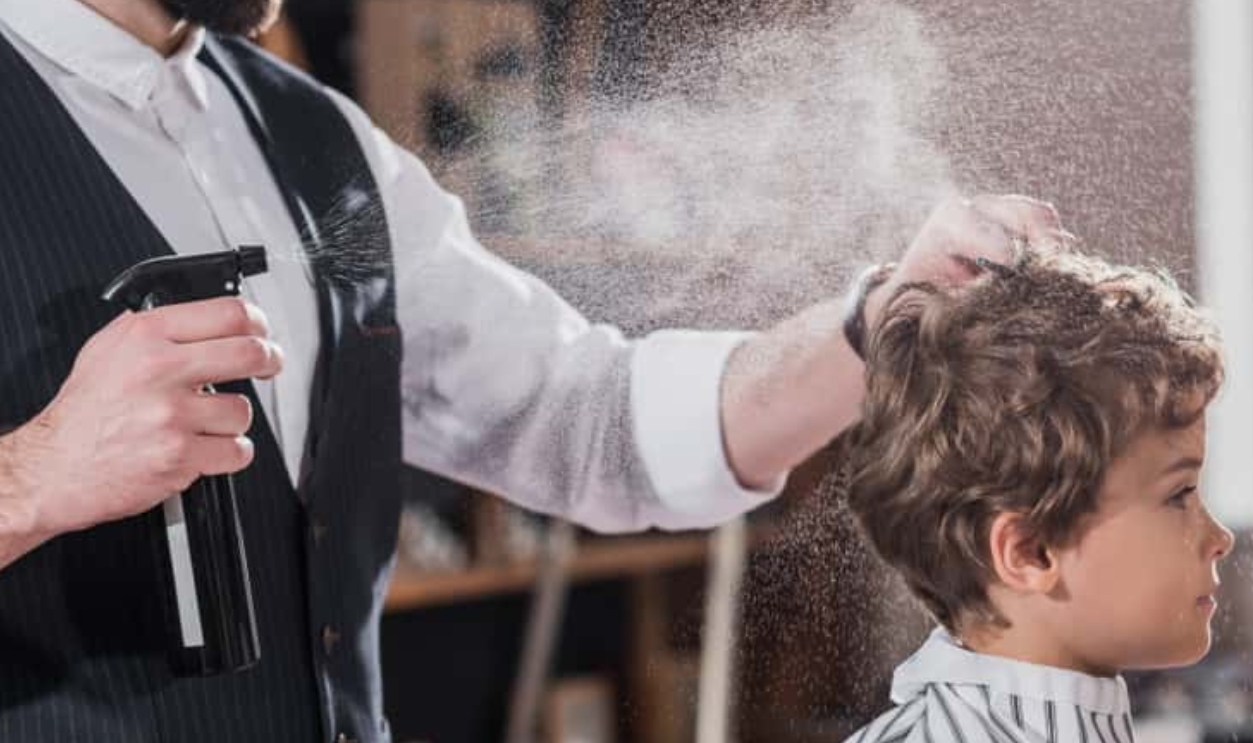 Smiling Bearded Barber Combing And Spraying Hair Of Little Kid, Shutterstock, 1077438848