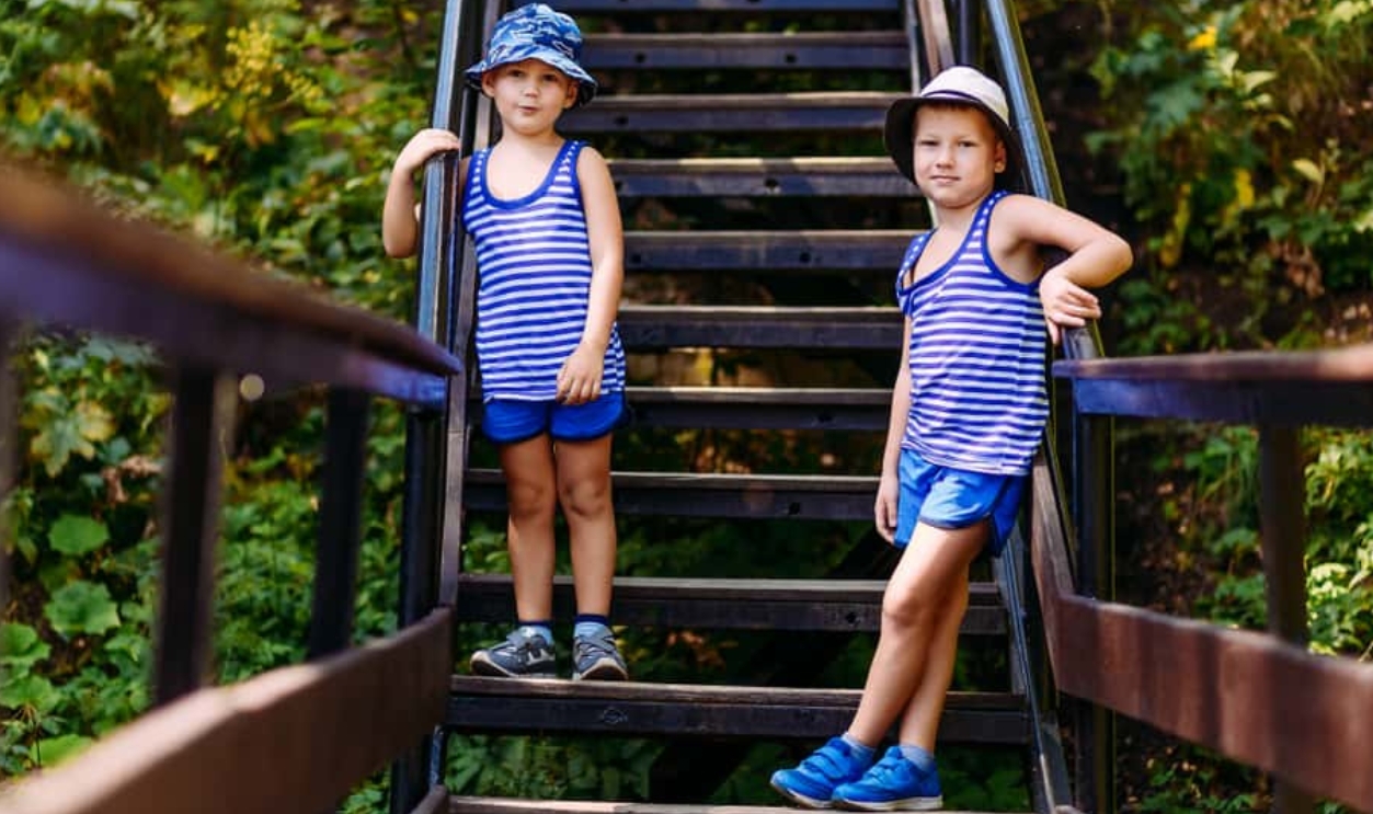 Two Boys In Striped T-Shirts And Blue Shorts Stand On The Stairs, Shutterstock, 1343397701