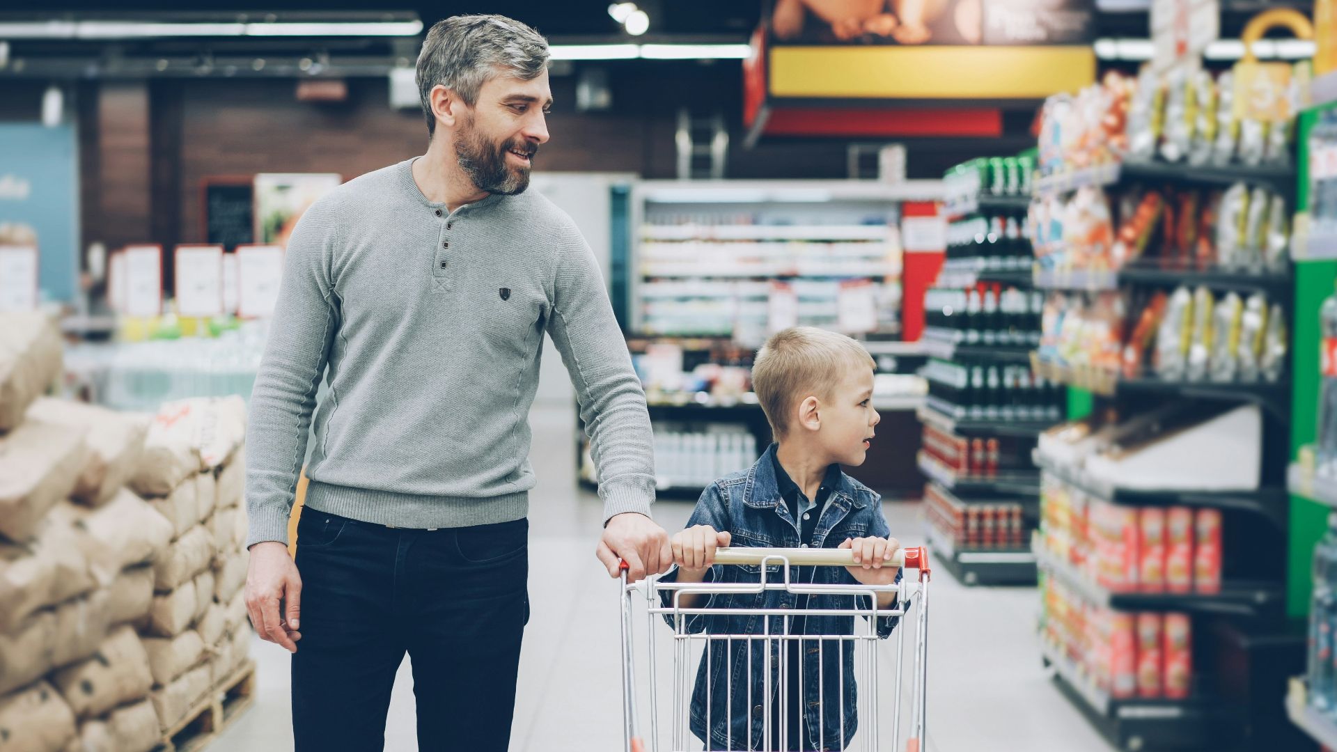 A father and son shop together in a supermarket.