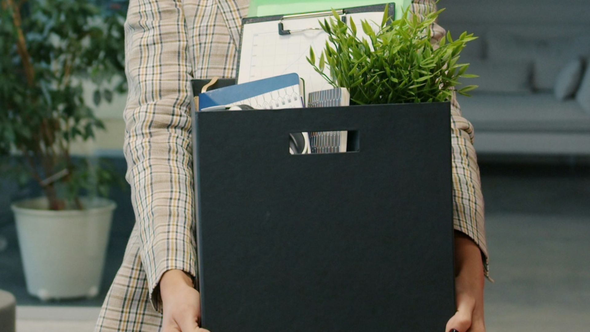 Woman carrying box of belongings leaving office