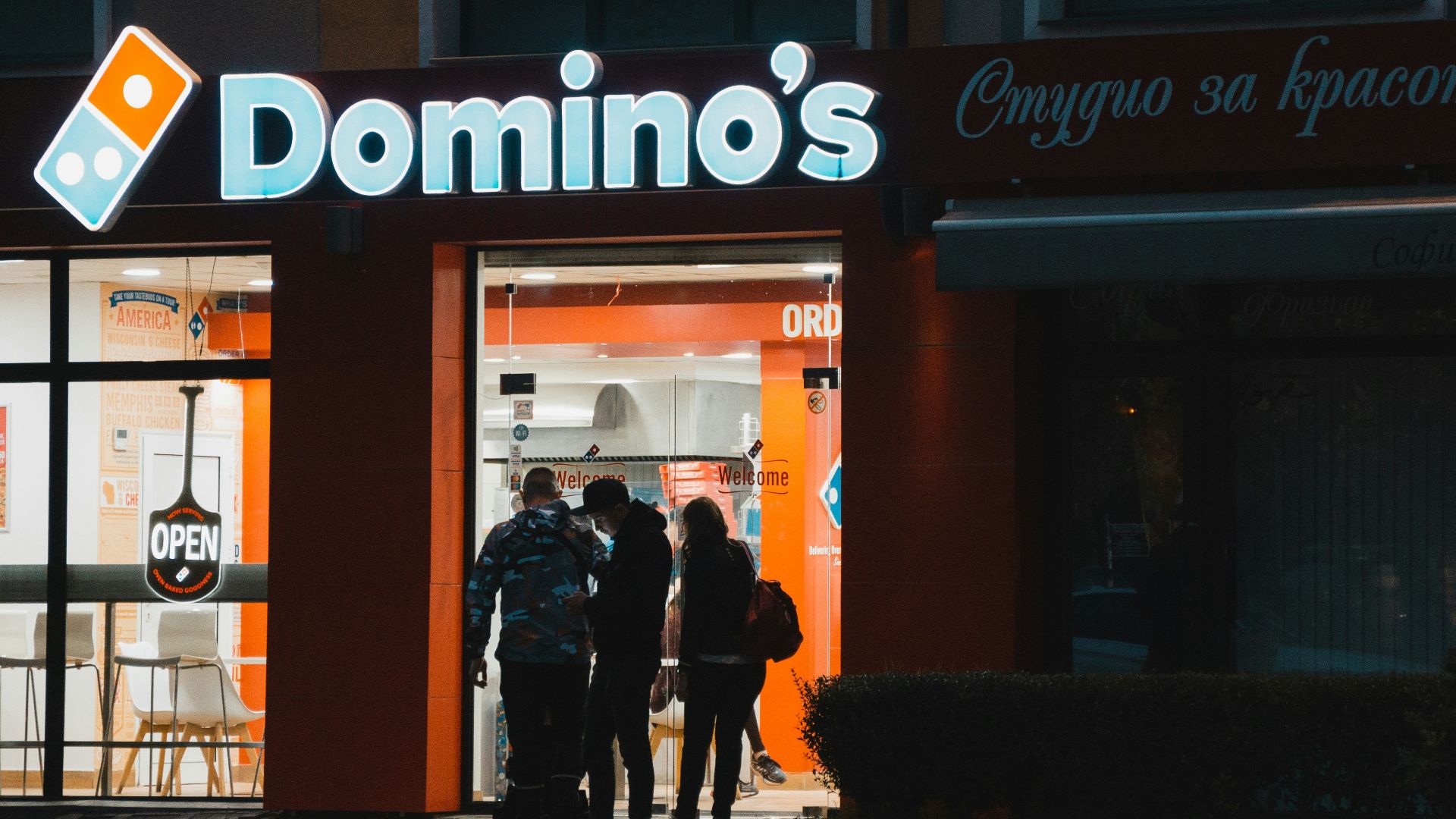 a group of people standing outside of a domino's store