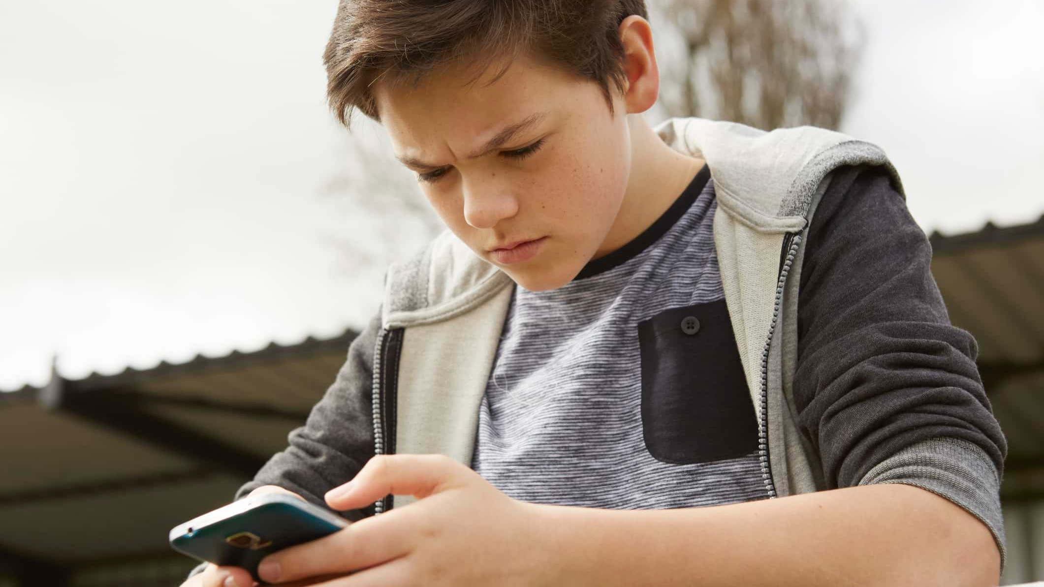 Anxious teenage boy reading smartphone text message.