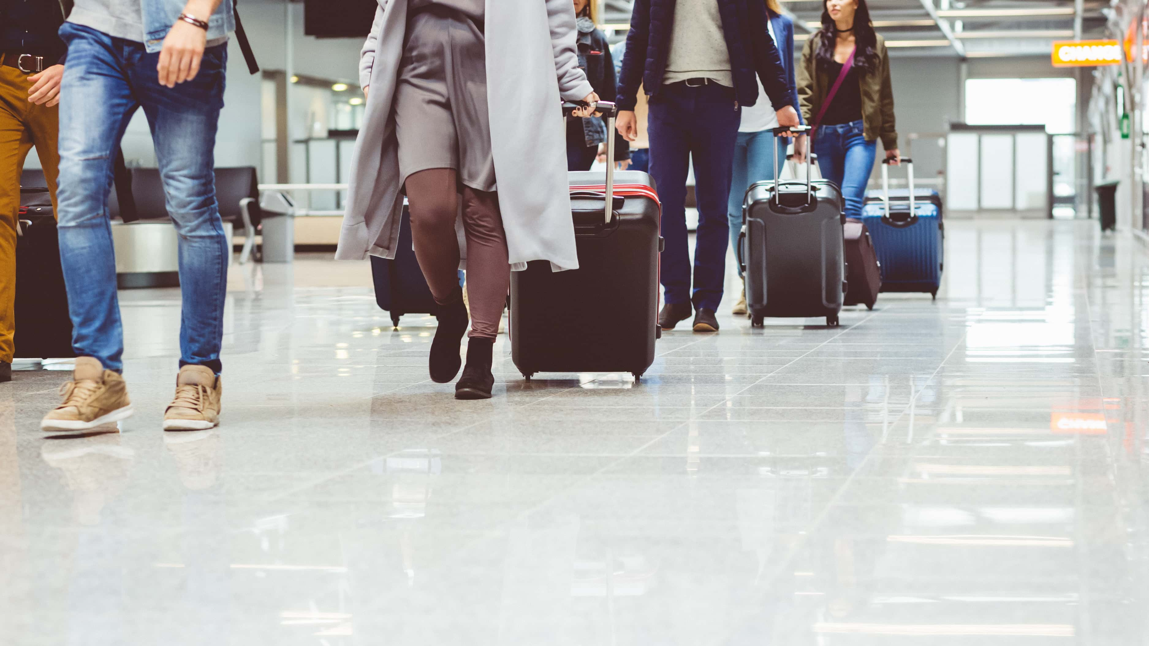 Group of people walking with suitcase at airport terminal.