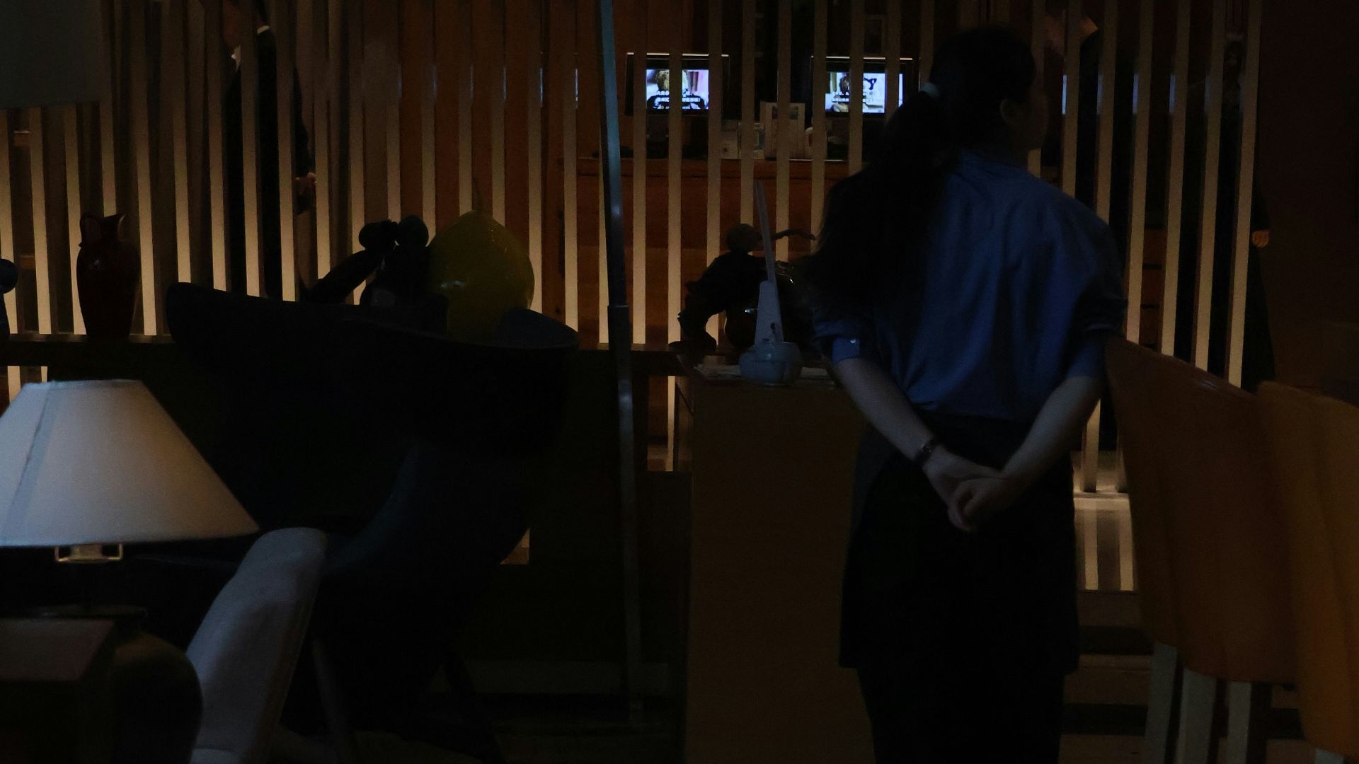 Person standing in a dimly lit lobby with wooden accents