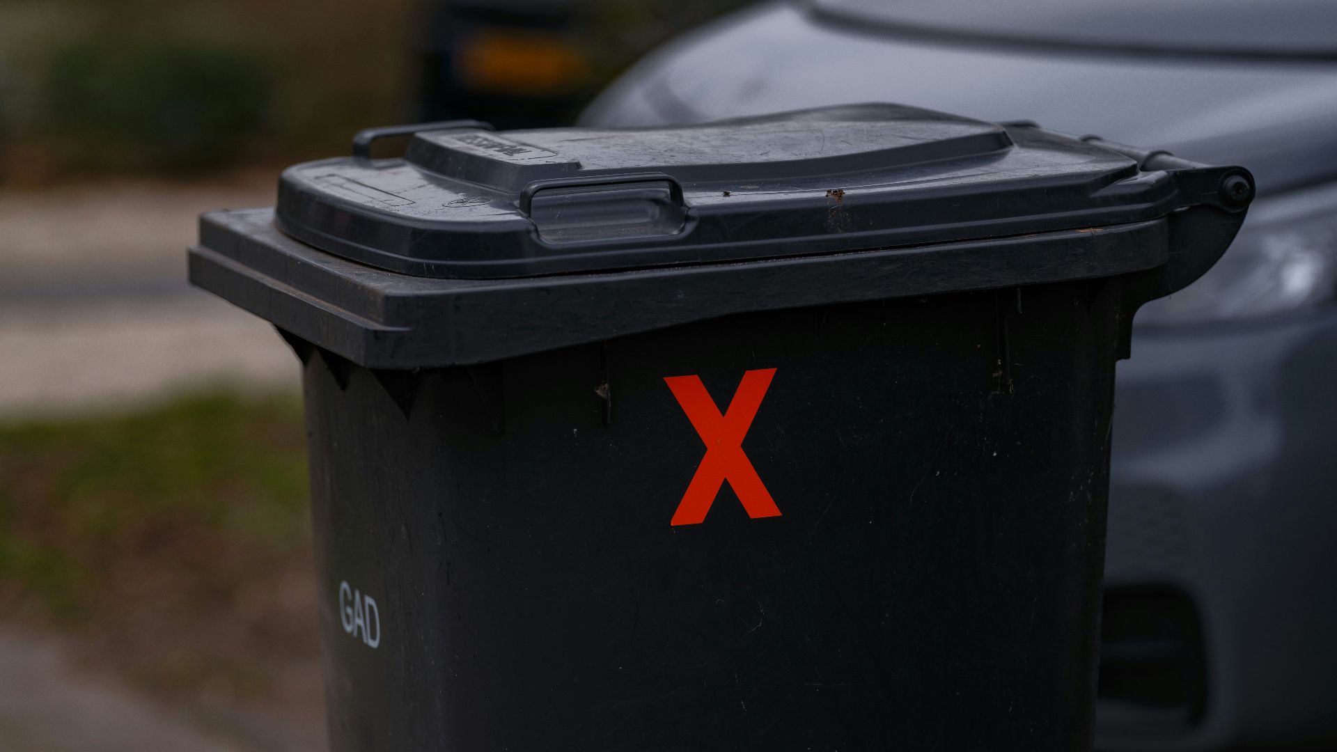 A black trash can sitting on the side of a road