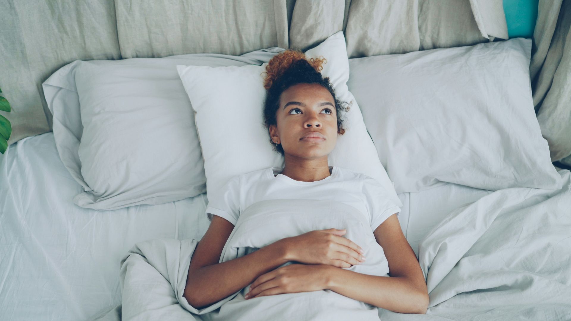 Young woman lying in bed with pillow.
