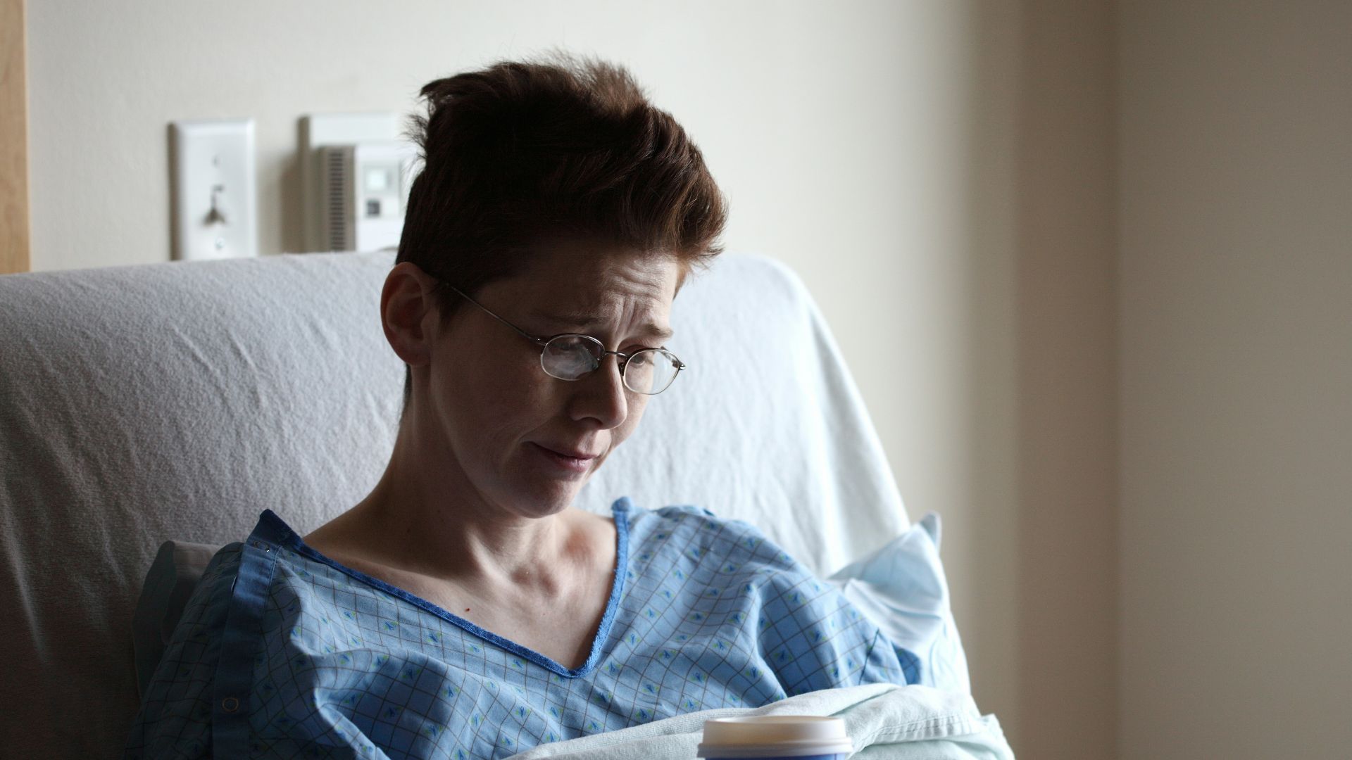 woman on bed holding plastic cup