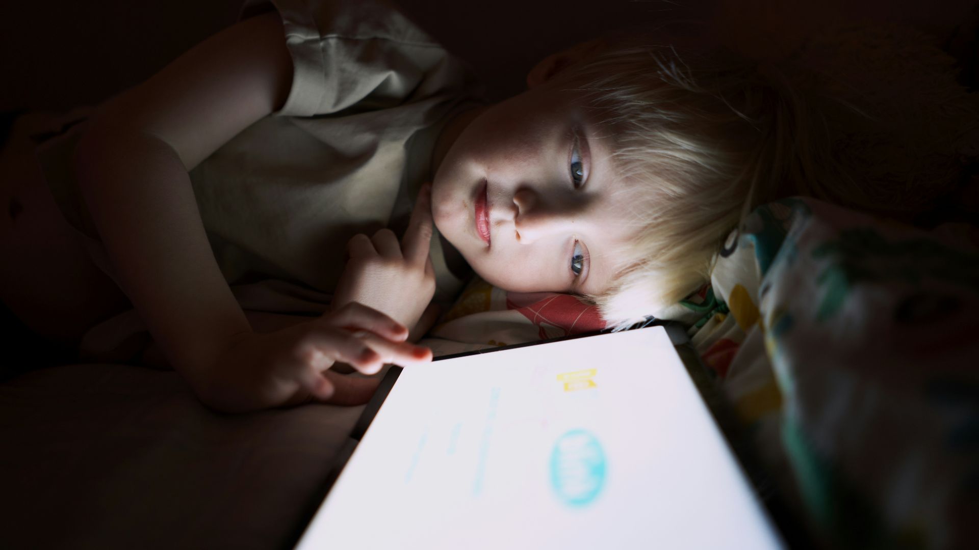a person lying on a bed with a tablet