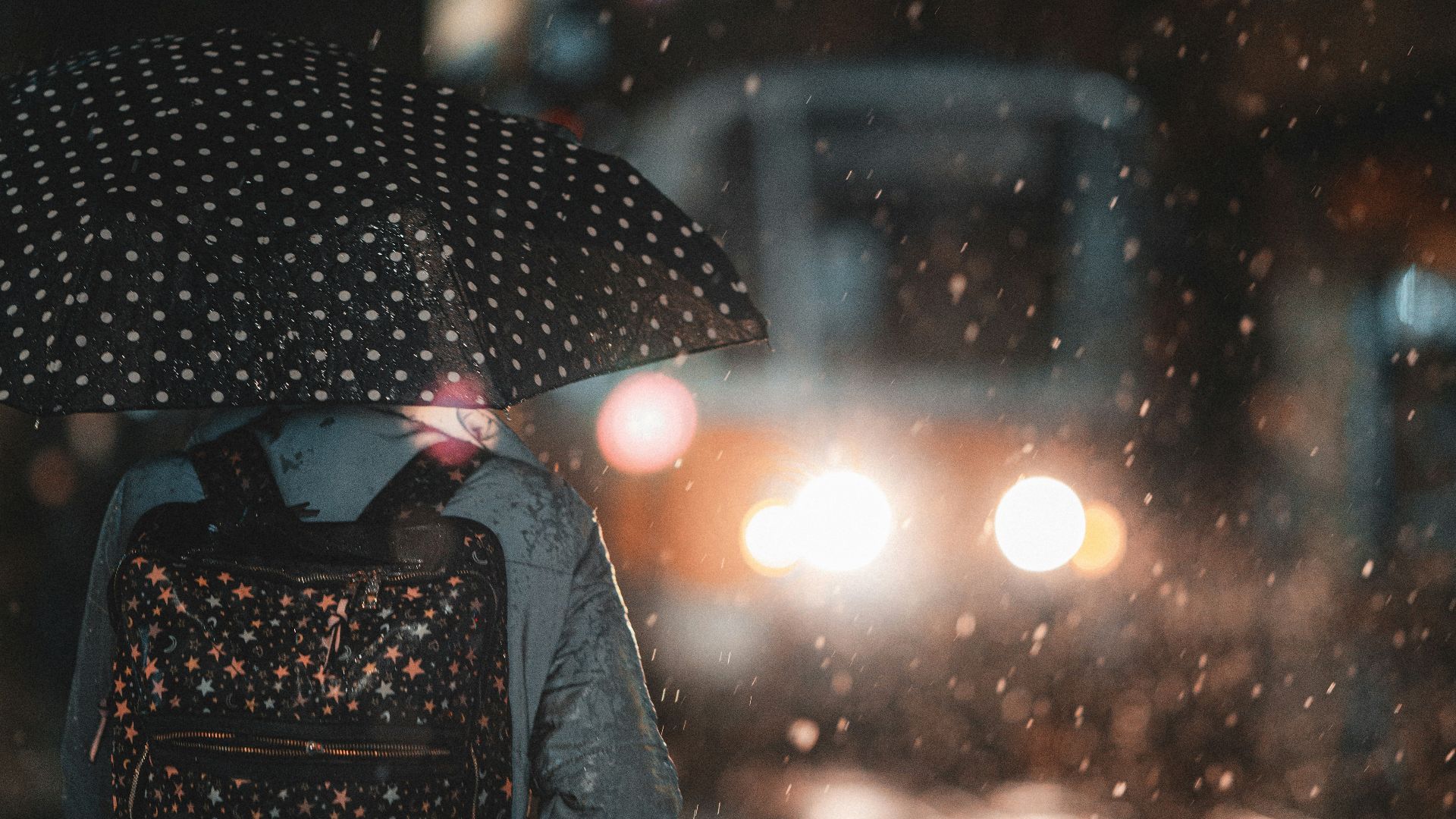 a person with a backpack and umbrella walking in the rain