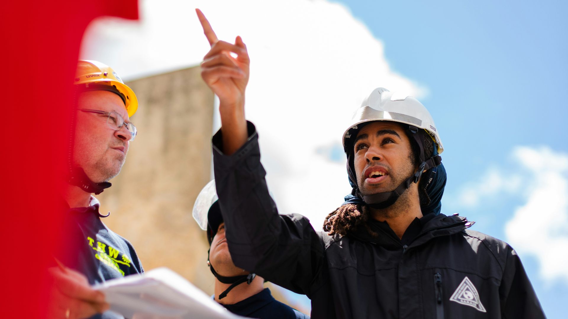 man in black jacket wearing yellow hard hat