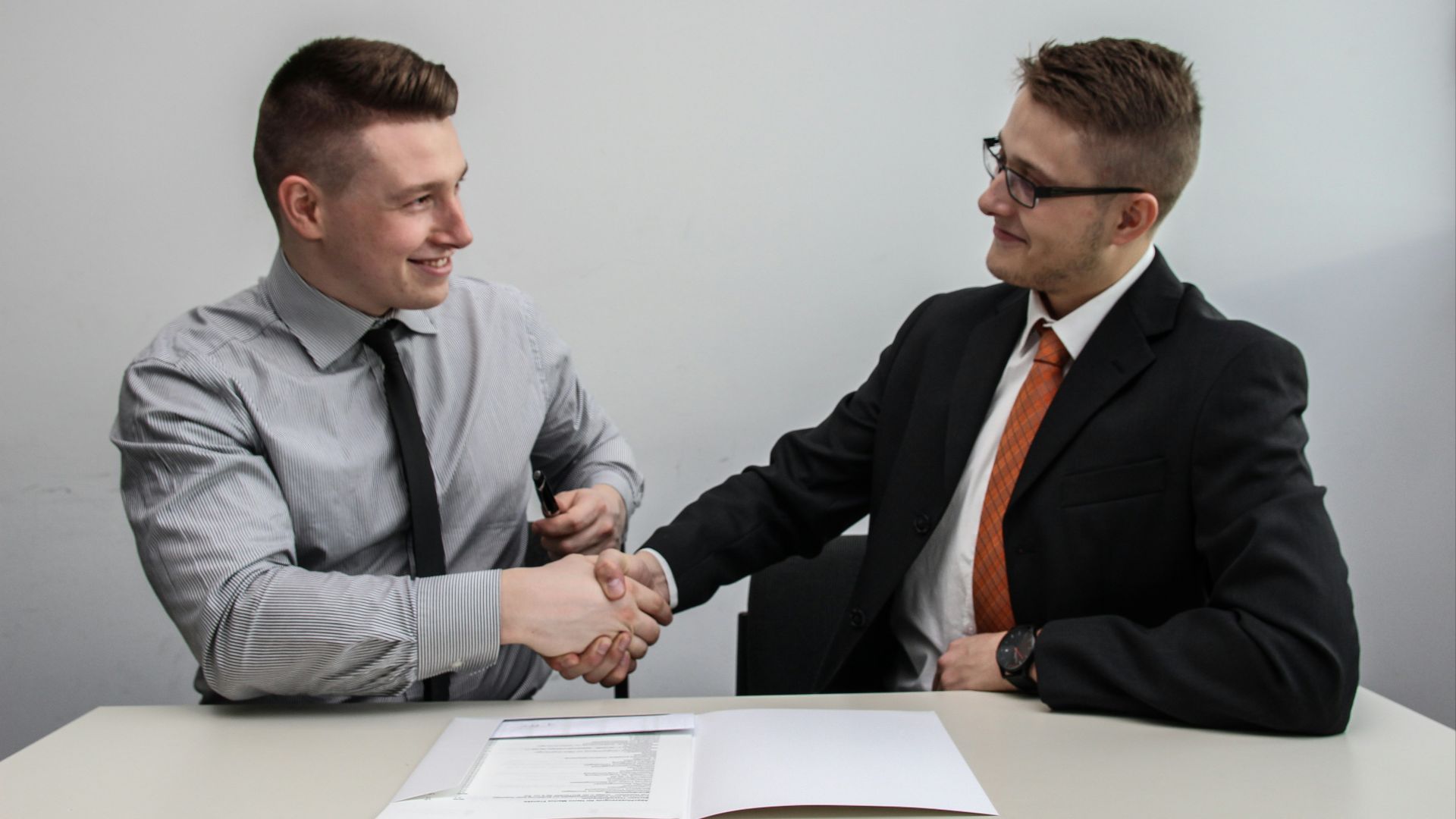 two men facing each other while shake hands and smiling