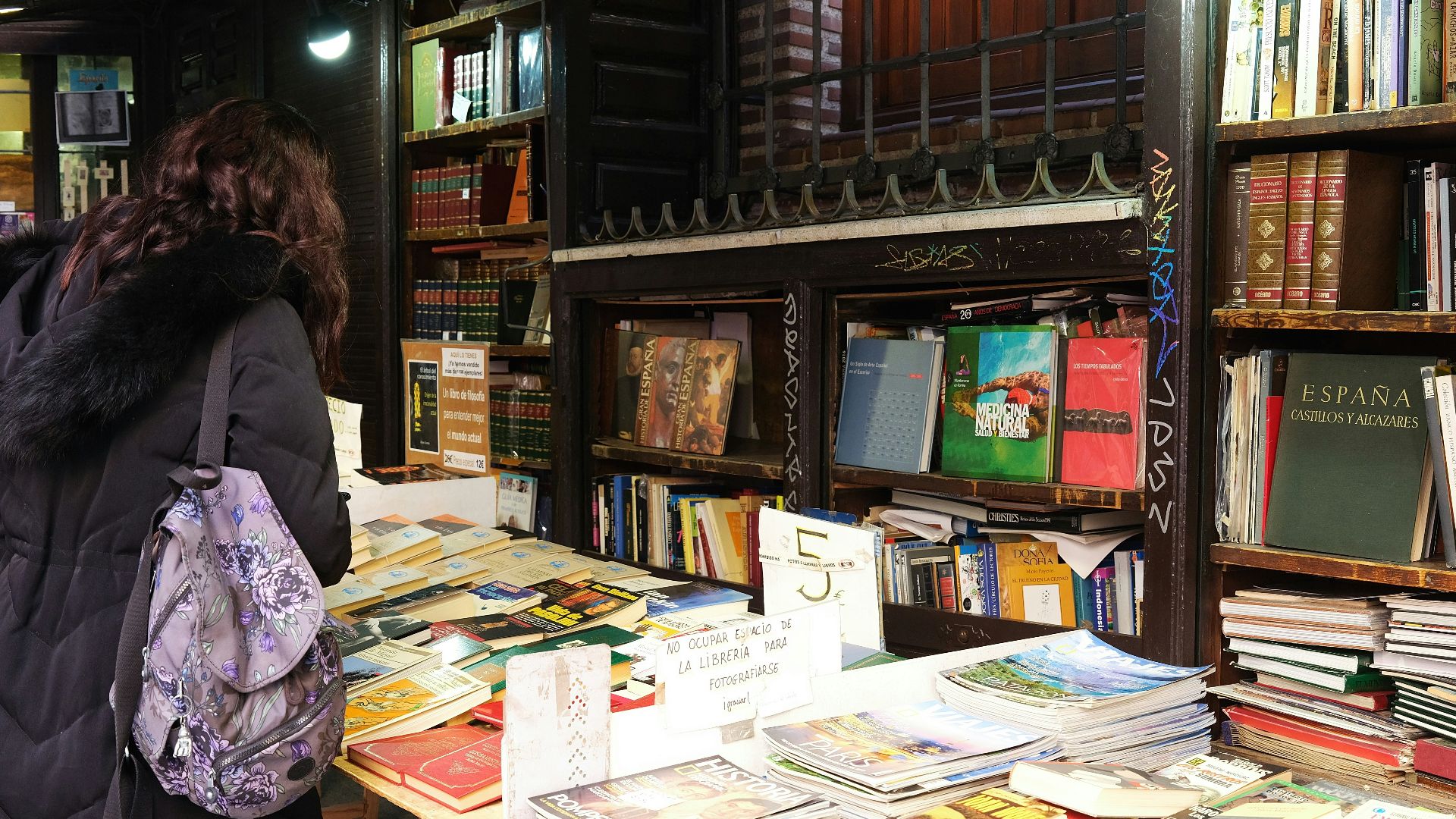 a woman standing in front of a table filled with books