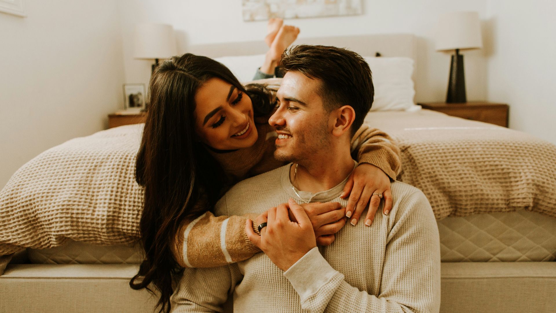 a man and a woman sitting on a bed together