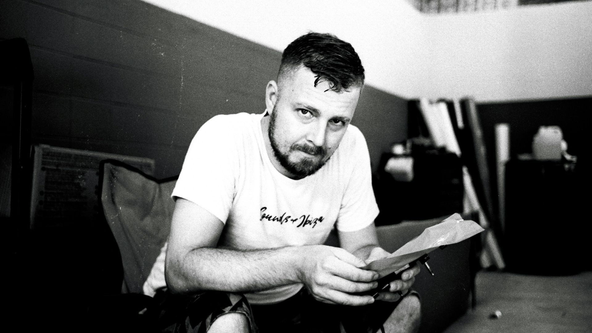 a man sitting on the floor looking at a piece of paper