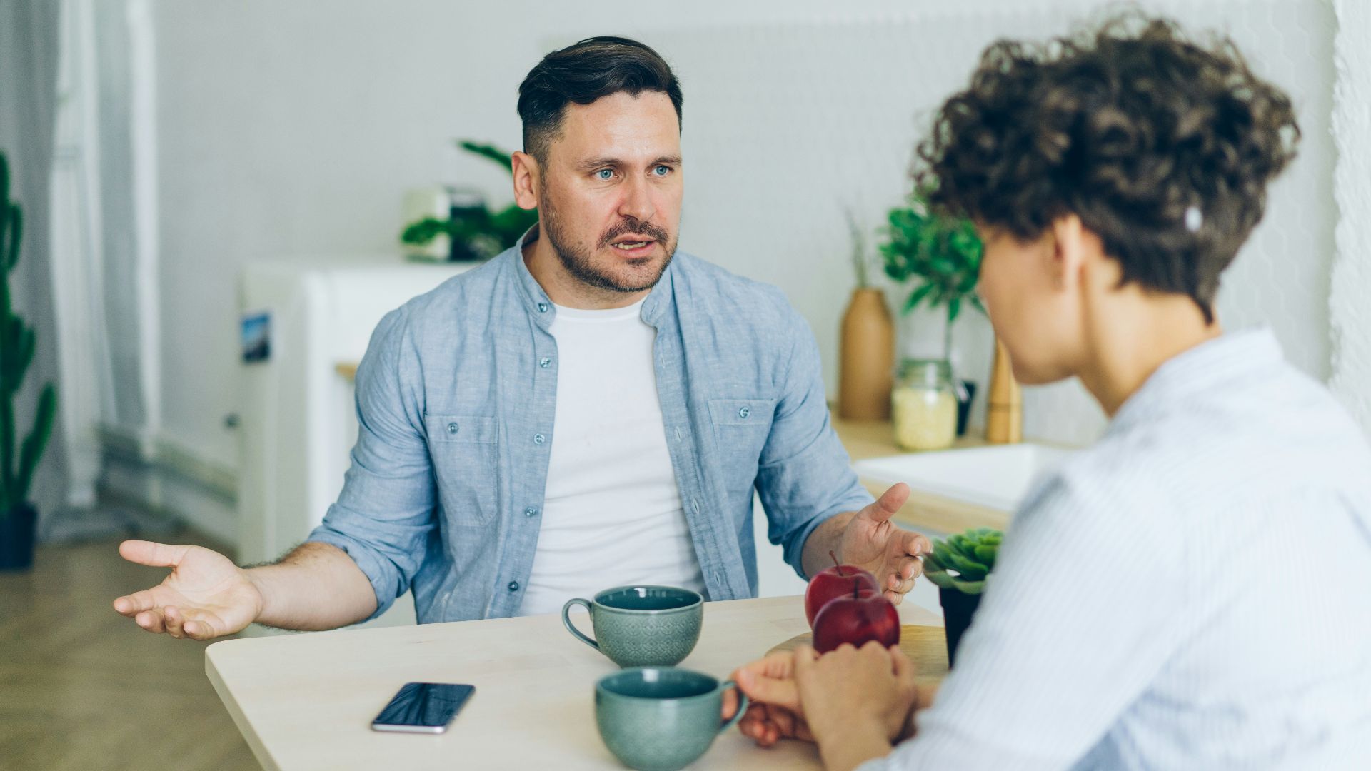 a man sitting at a table talking to a woman