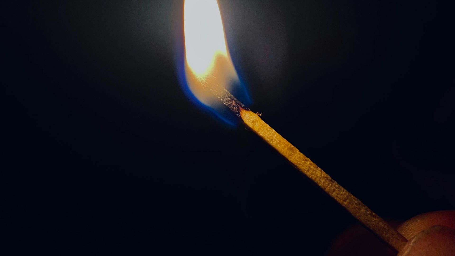 a lit matchstick in the dark with a lit match