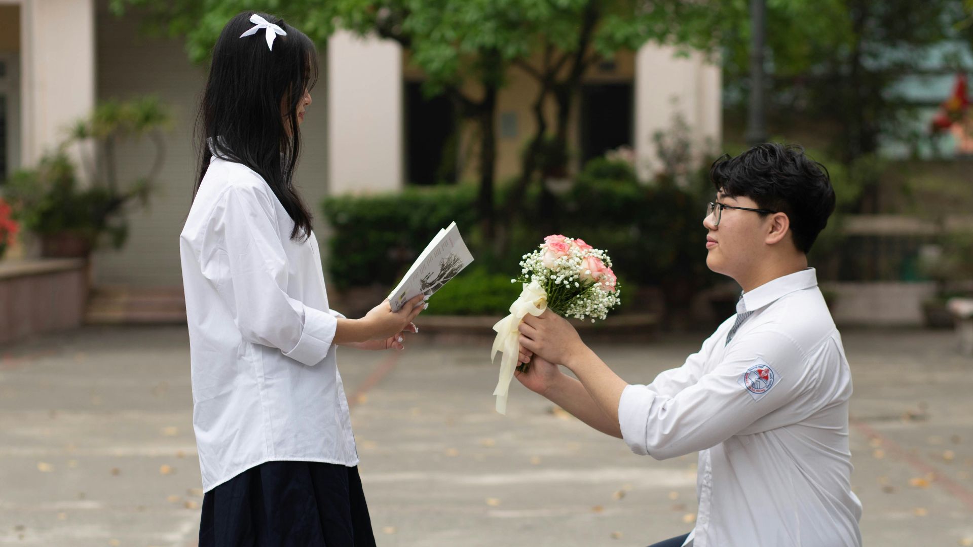 a man kneeling down next to a woman holding flowers