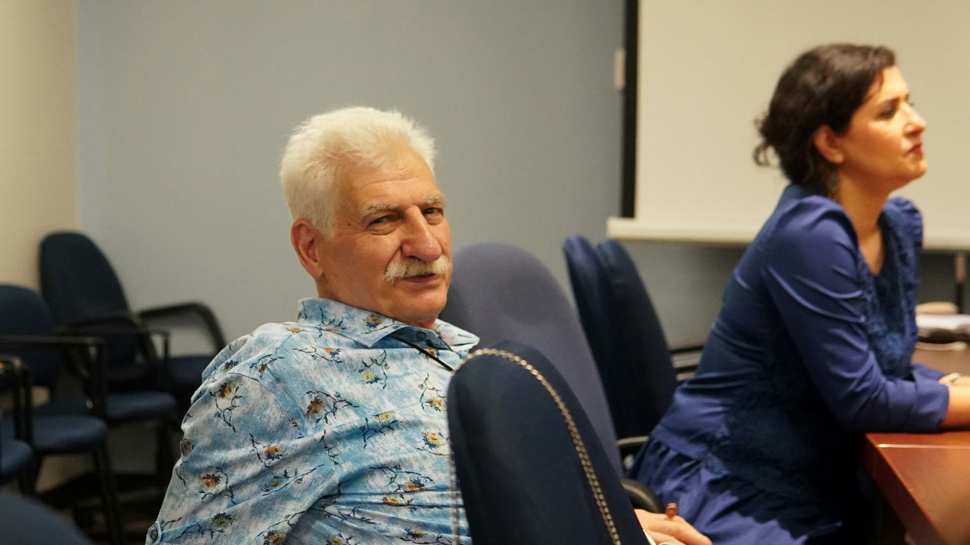 An older man and woman in a meeting room.