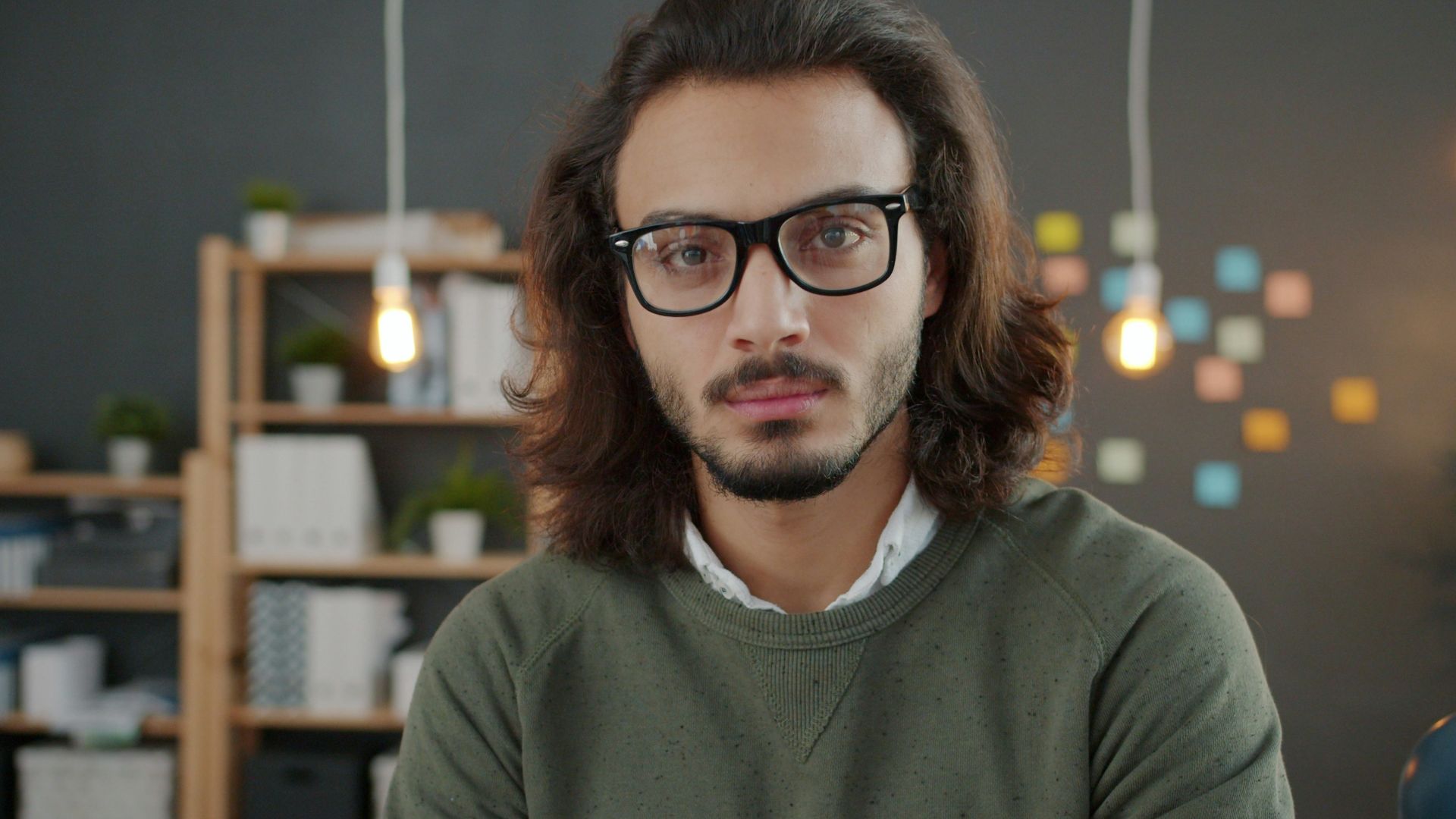 Man with glasses and long hair in office
