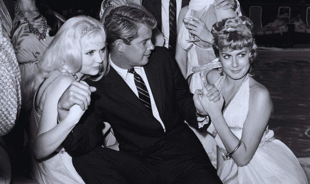 Gettyimages - 3202666, Troy In Clover 1960: American actors Troy Donahue (1936 - 2001, foreground) and Peter Brown pose with women dressed in Grecian costumes, near a swimming pool at a party for director Pietro Francisci's film, 'Hercules Unchained,' Beverly Hills Hotel, California. 
