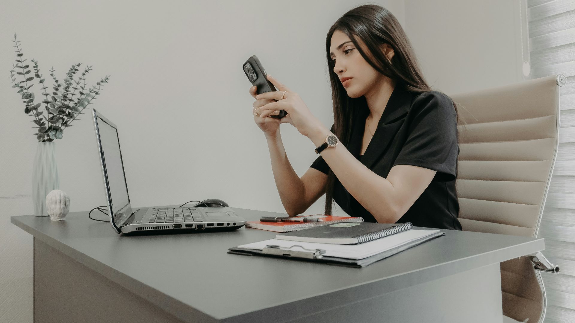 A woman using her phone at a desk