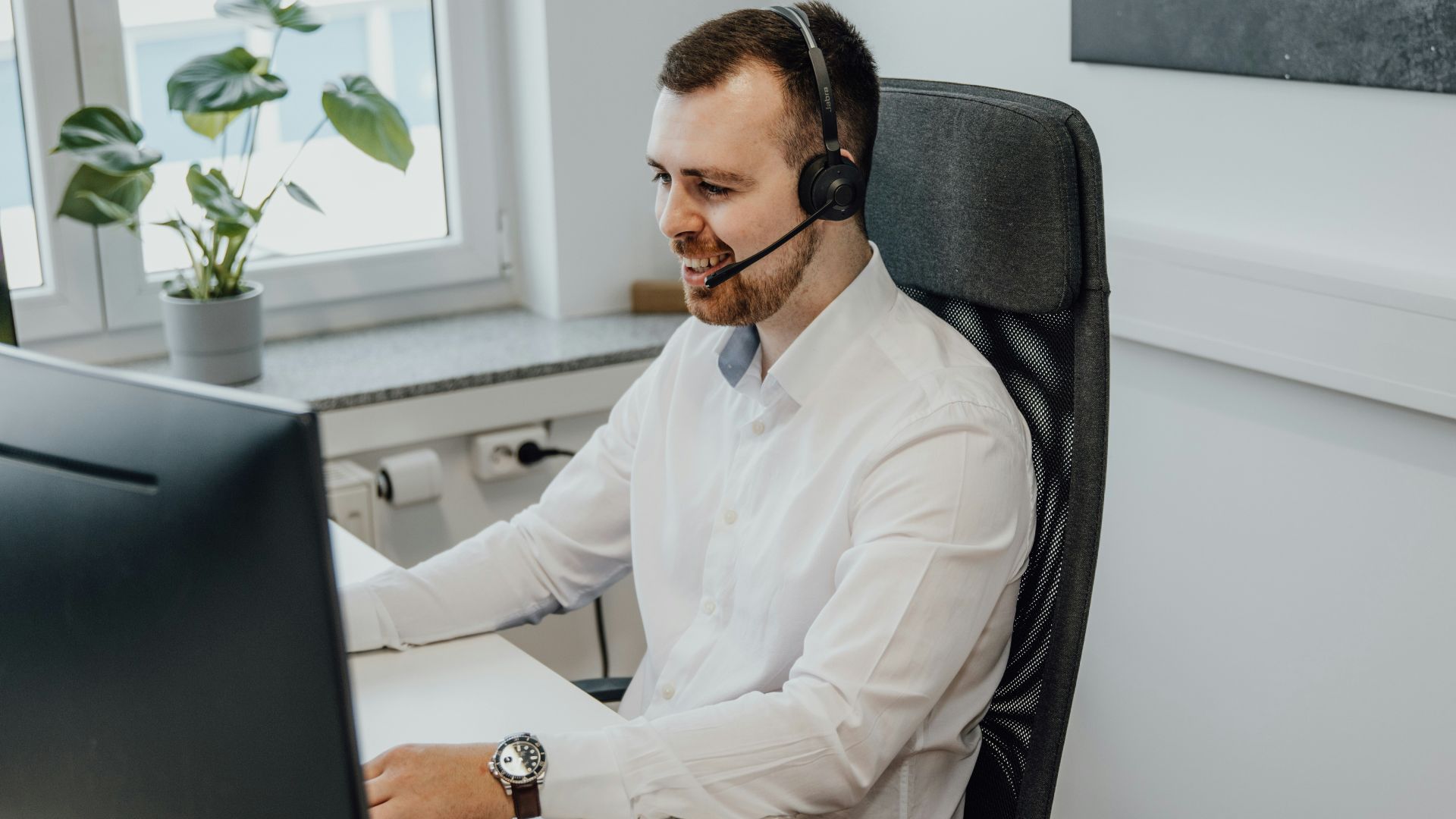 a man wearing a headset sitting in front of a computer
