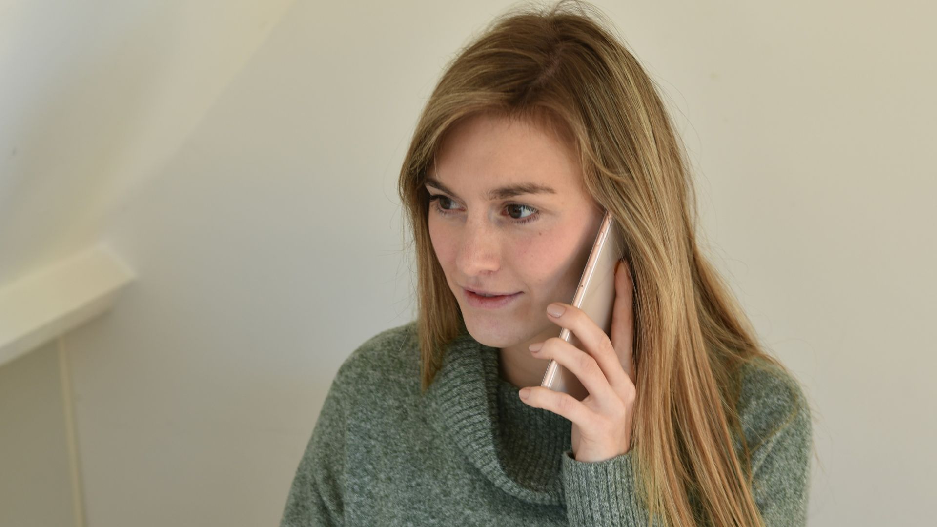 a woman sitting in front of a computer talking on a cell phone