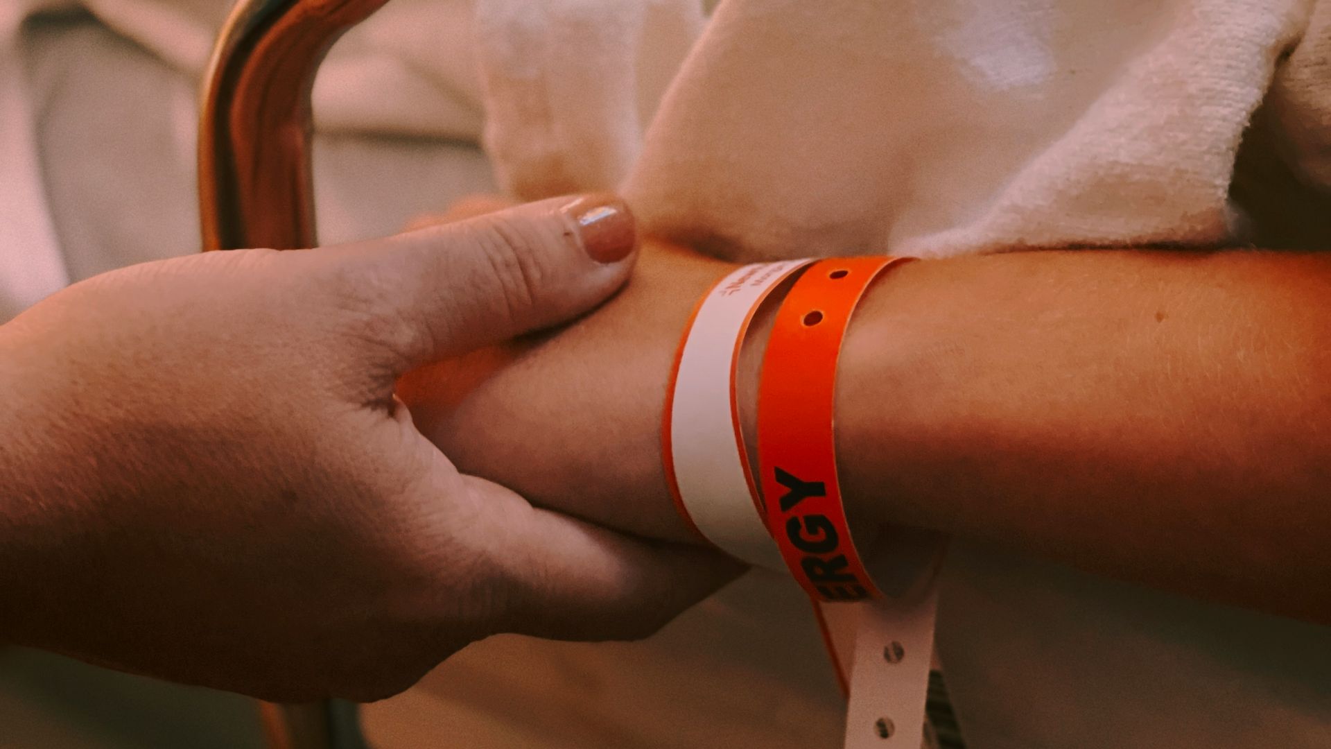person wearing orange and white silicone band