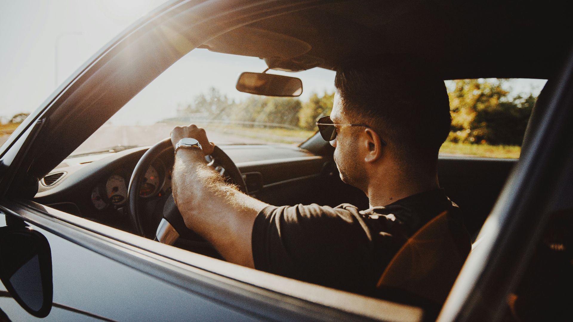 man in black jacket driving car during daytime