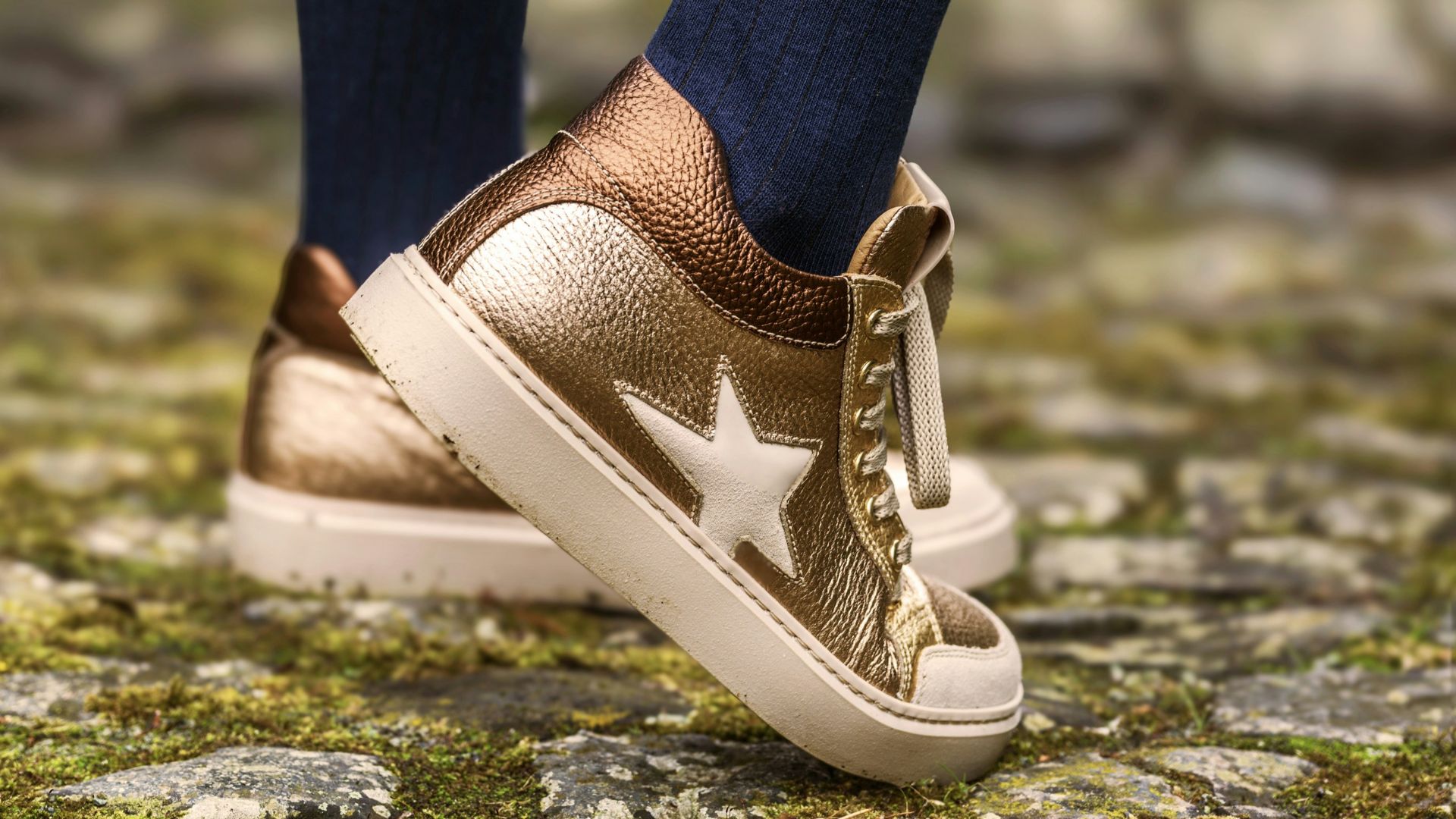 Gold sneakers with a star and striped socks.